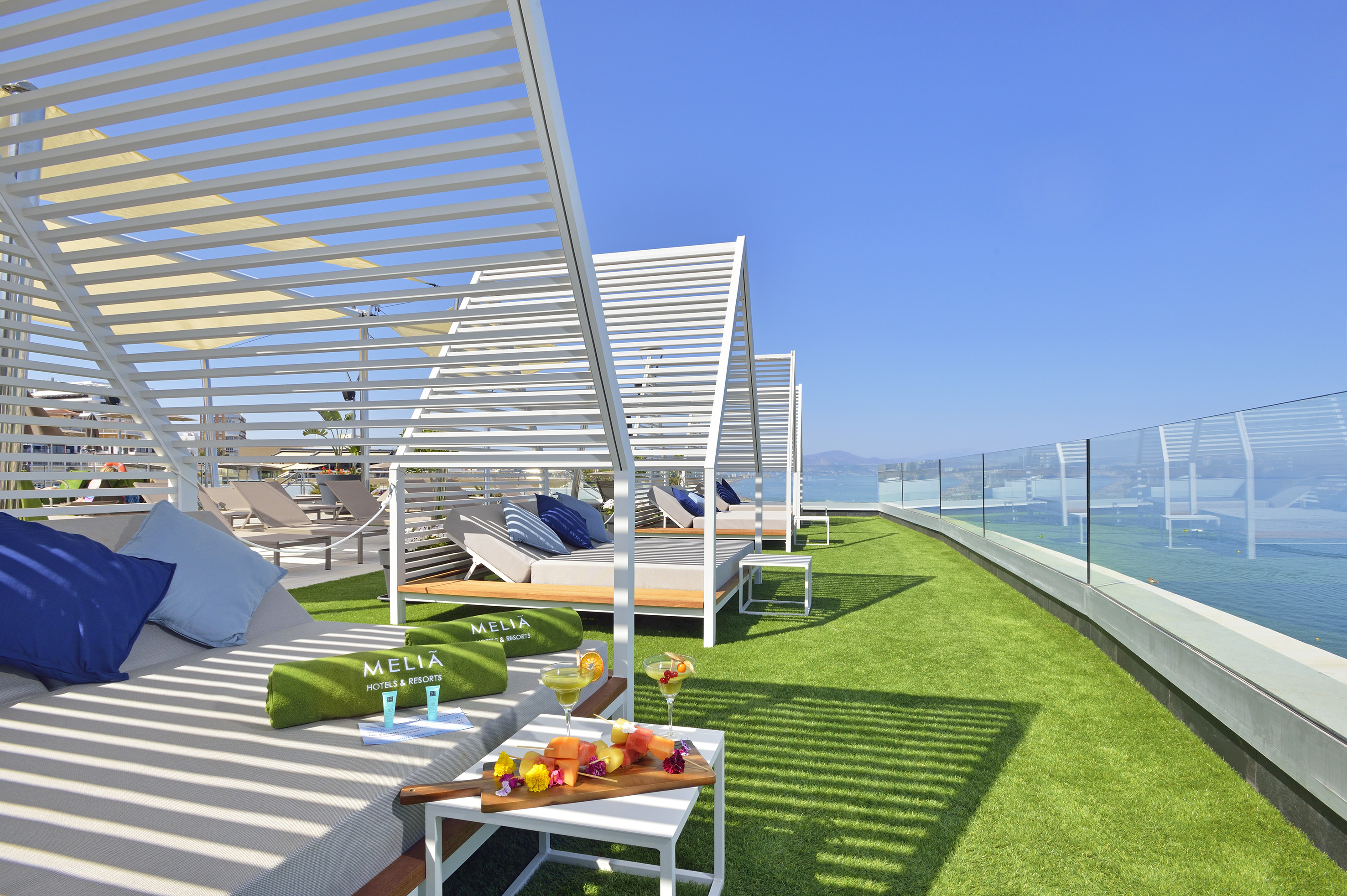 a deck with lounge chairs and a table on a green lawn
