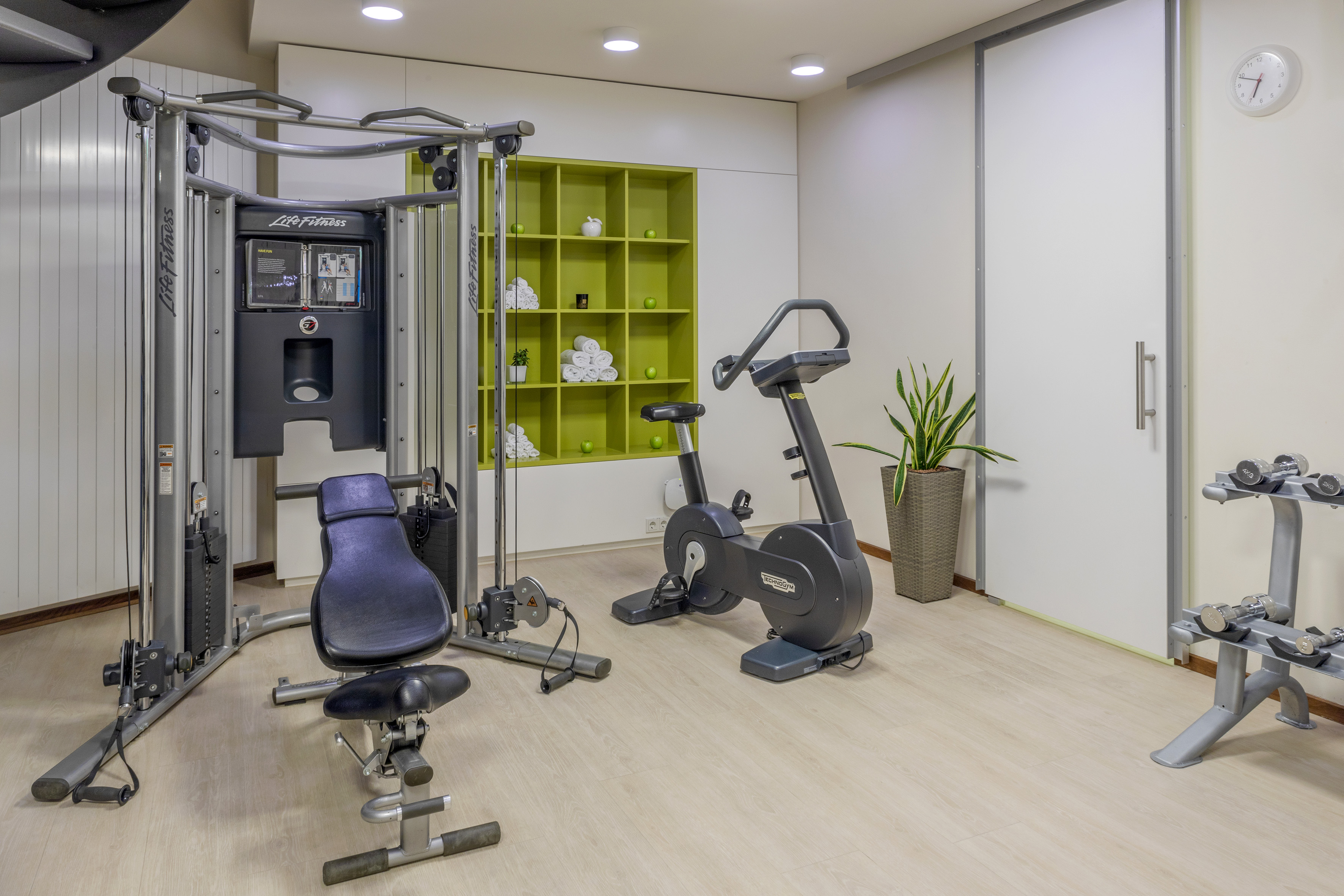 Well-equipped home gym with multi-station fitness machine, exercise bike, and dumbbells.