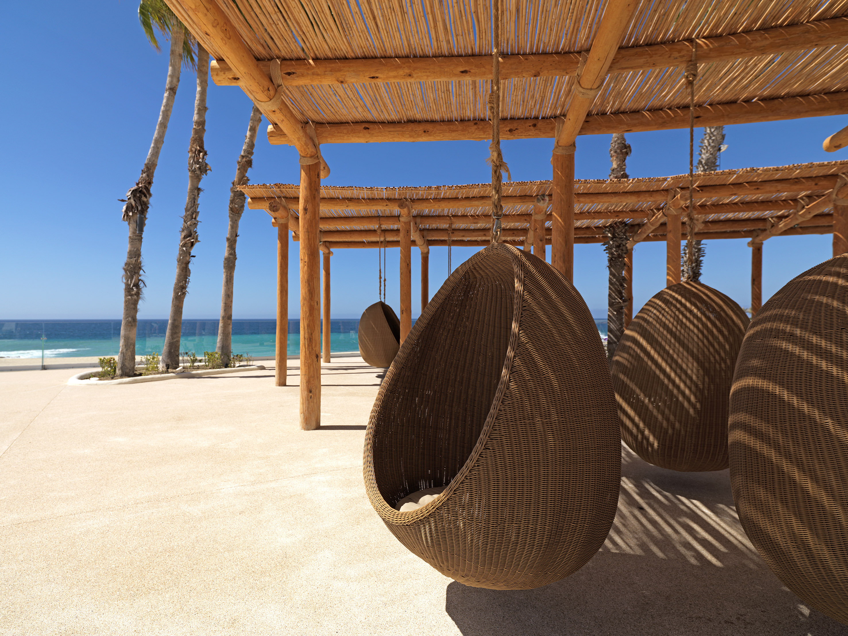 a wicker chairs from a roof on a beach
