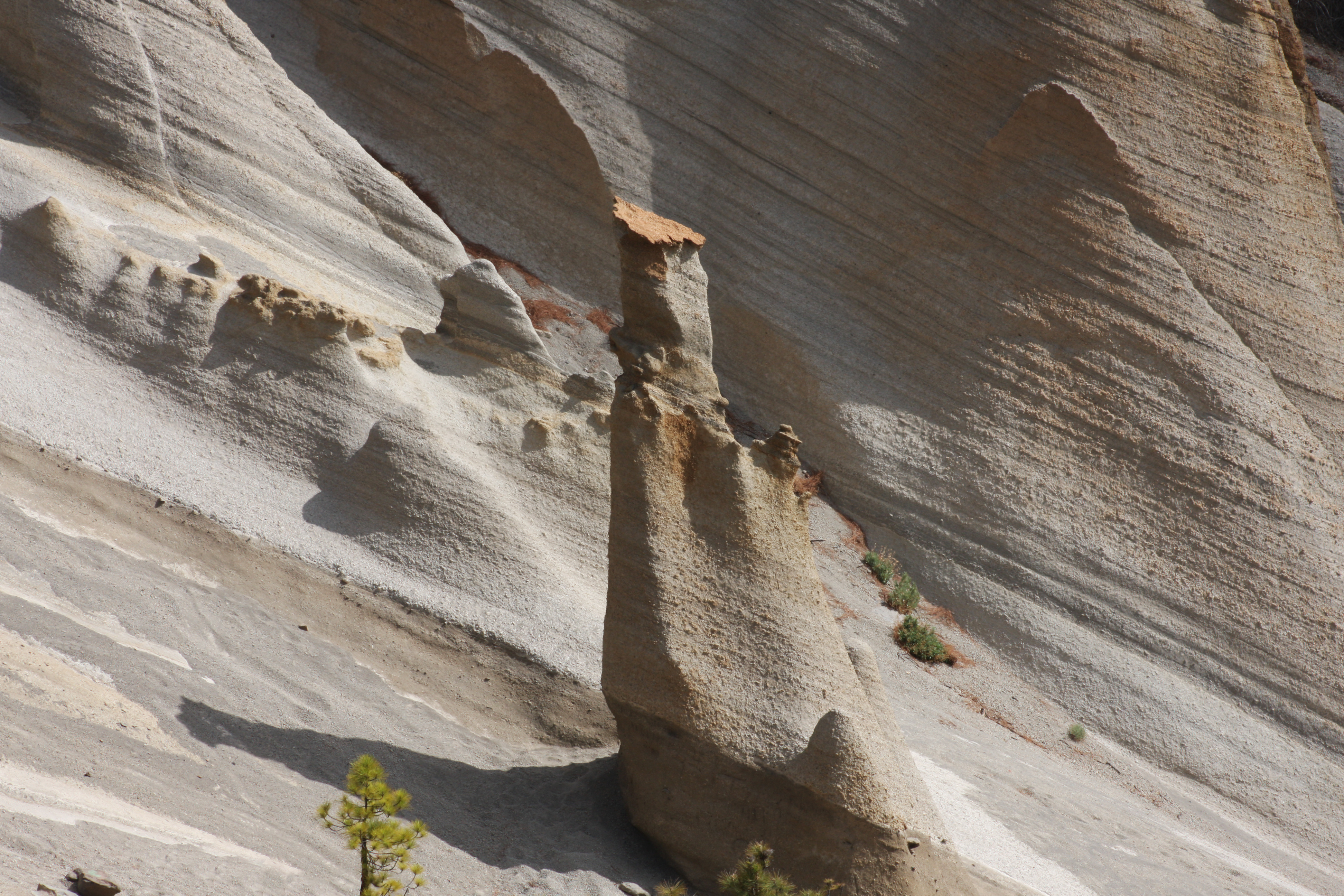 Eroded rock hoodoo against layered volcanic ash formations.