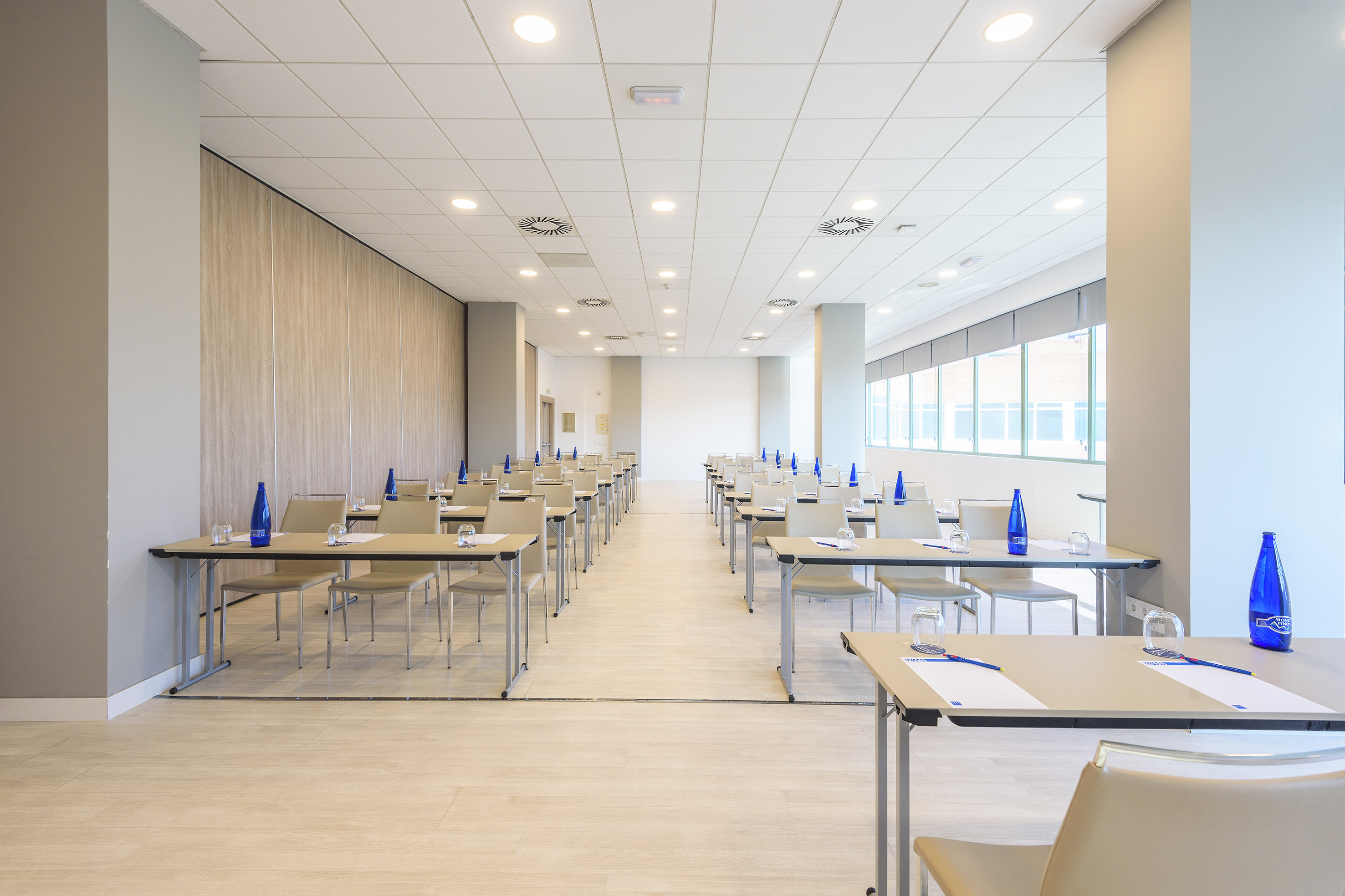 Modern conference room set up classroom style with tables and blue water bottles.