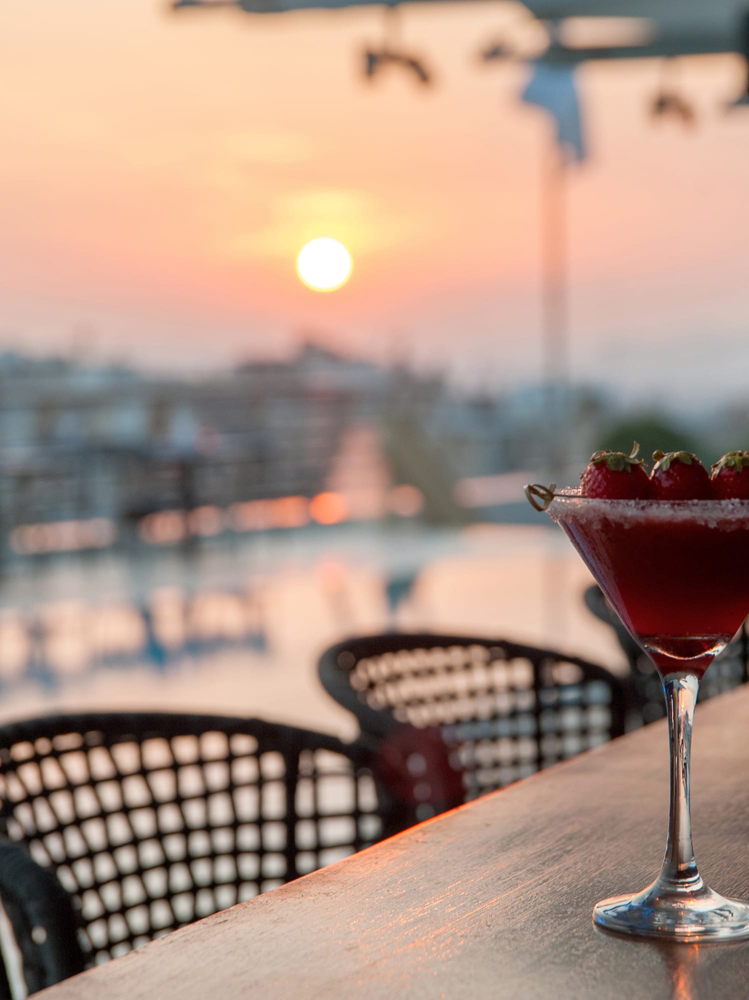 a glass of red liquid and strawberries on a table