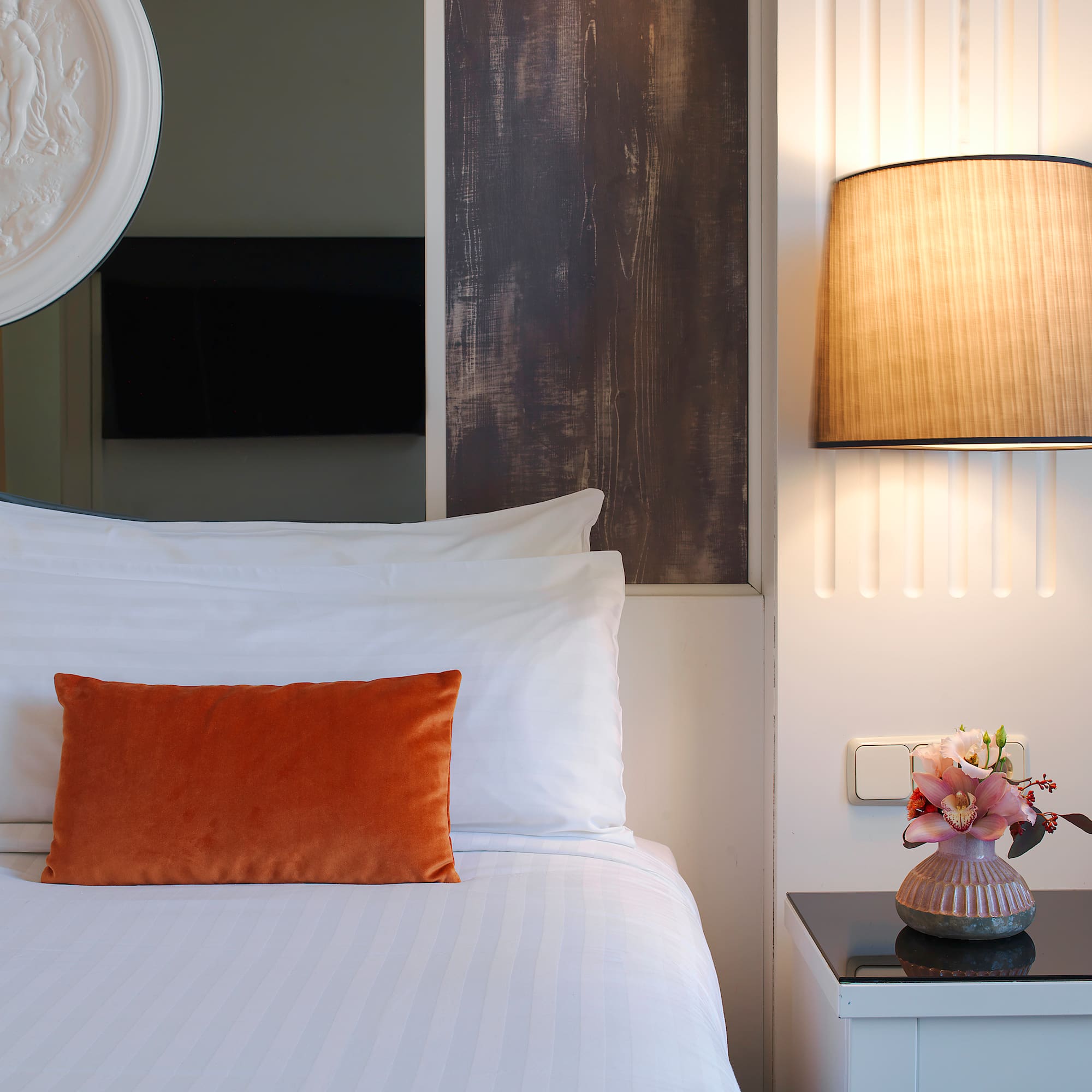 a bed with a vase of flowers on a table