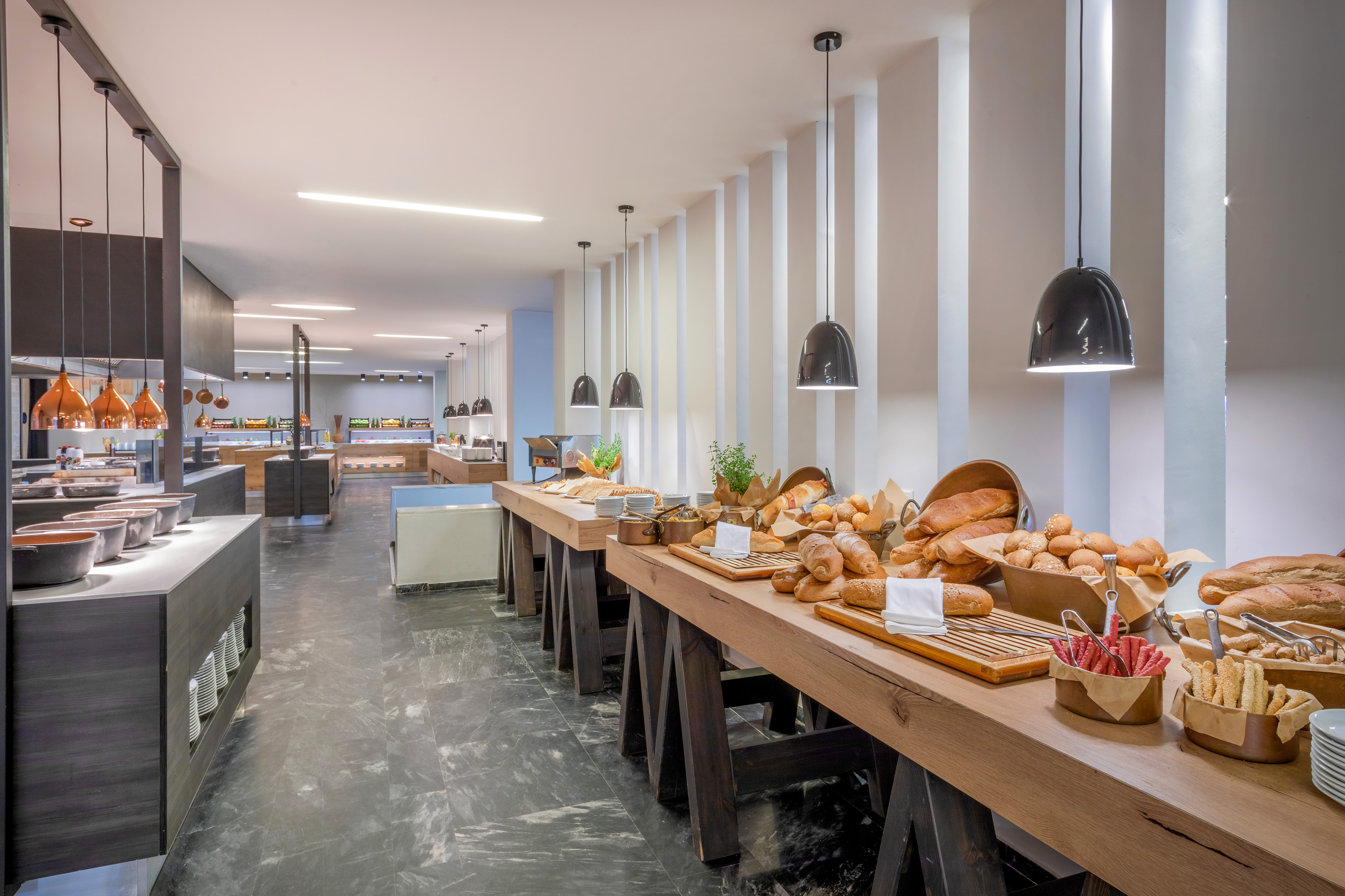 Hotel breakfast buffet with fresh bread and pastries on wooden counters.