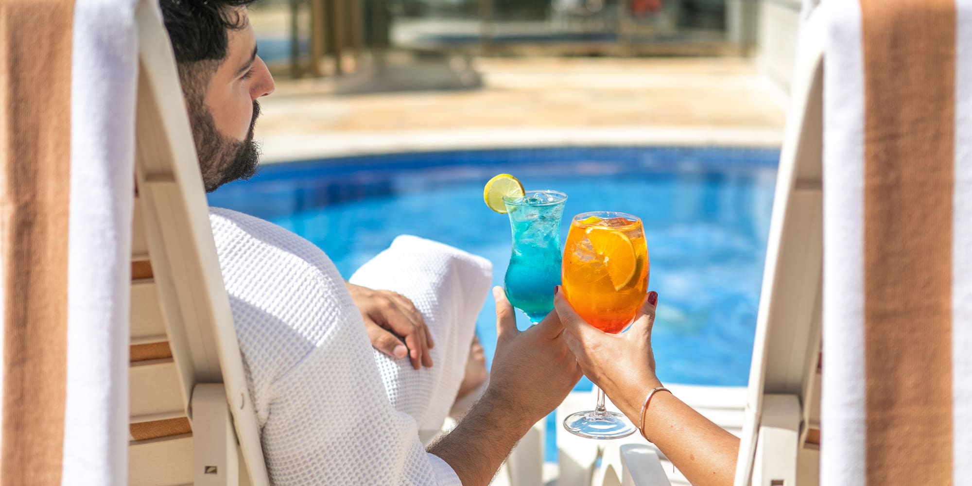 a man and woman sitting in chairs with drinks in their hands
