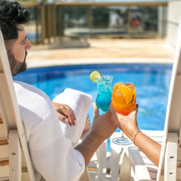 a man and woman sitting in chairs with drinks in their hands