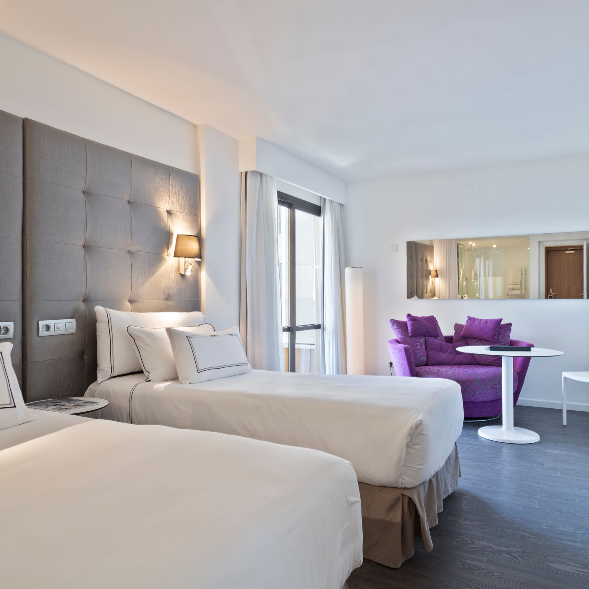 a room with two beds and a purple chair