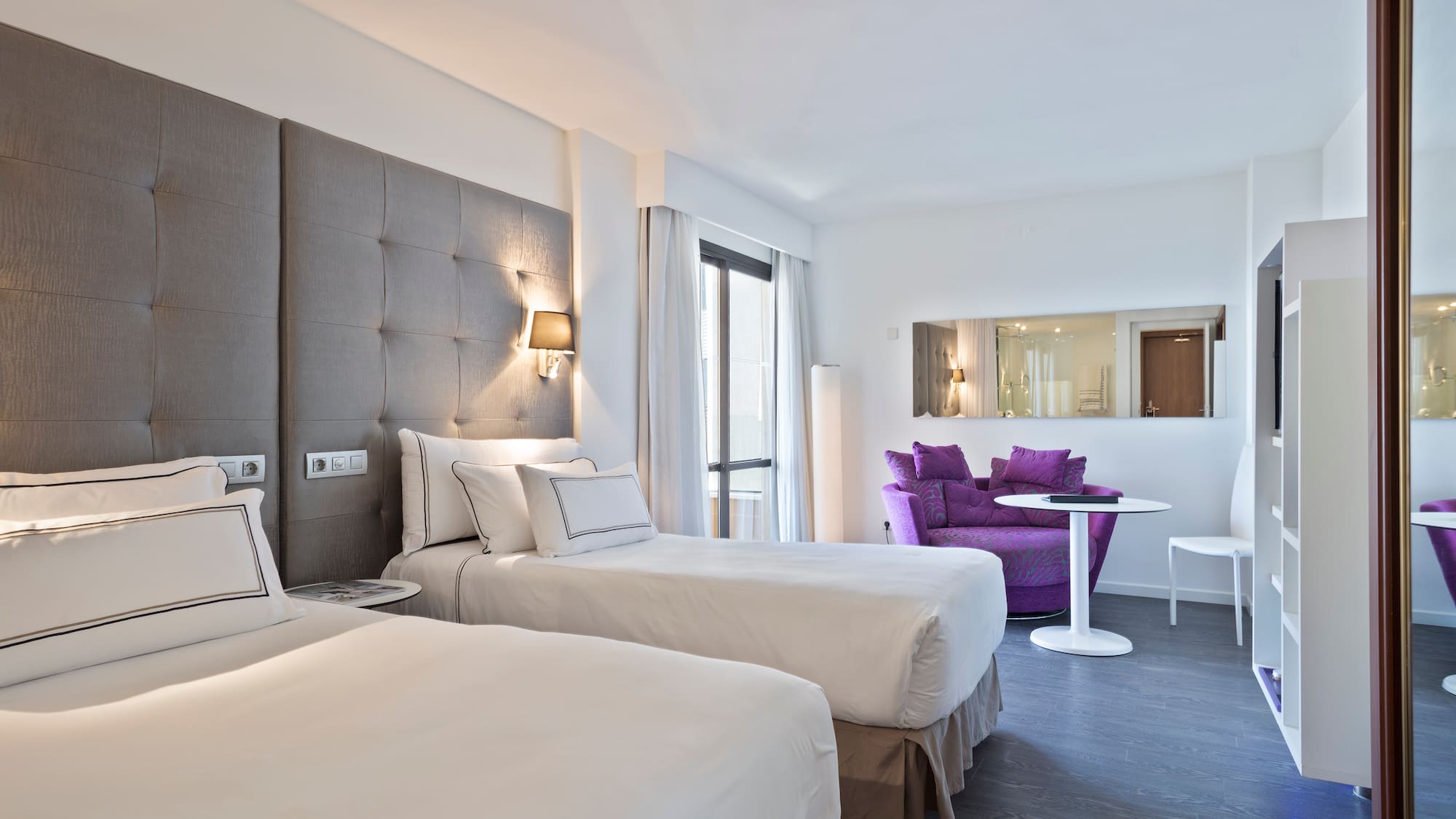 a room with two beds and a purple chair