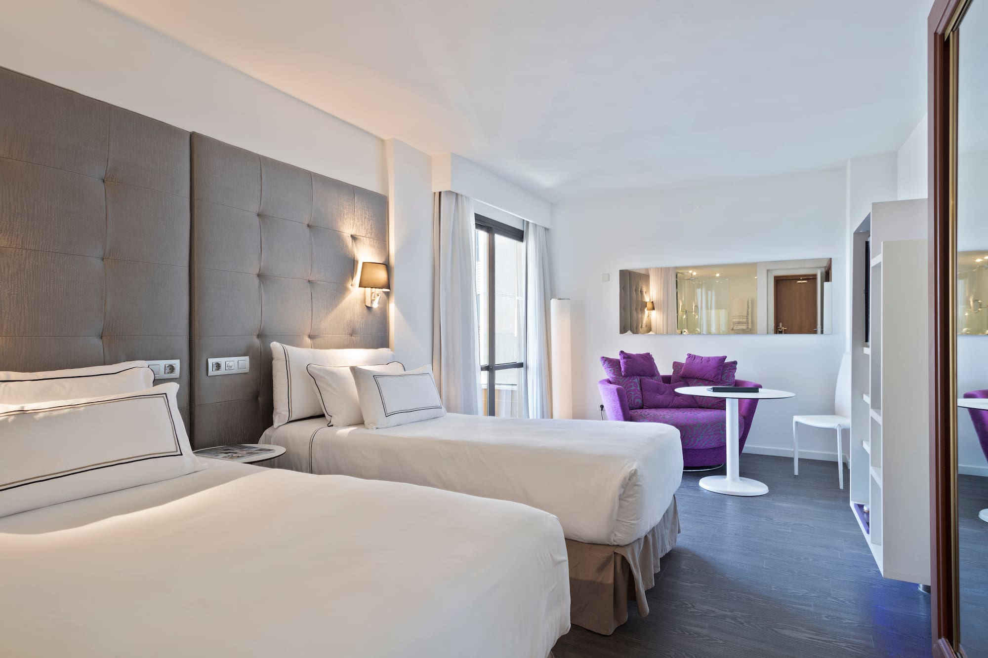 a room with two beds and a purple chair