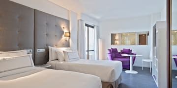 a room with two beds and a purple chair