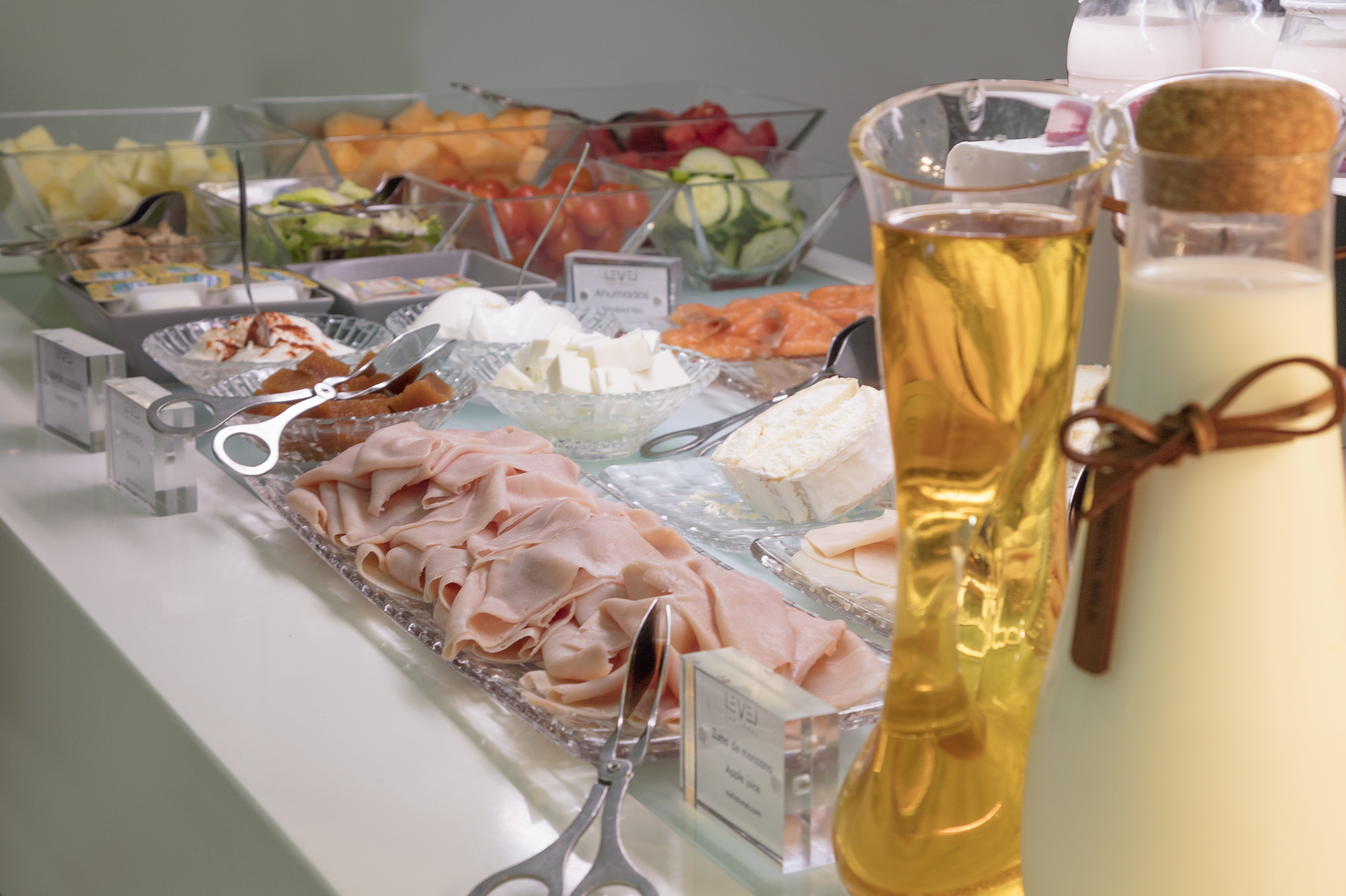 Hotel breakfast buffet with ham, cheeses, salmon, fruits, vegetables, juice.