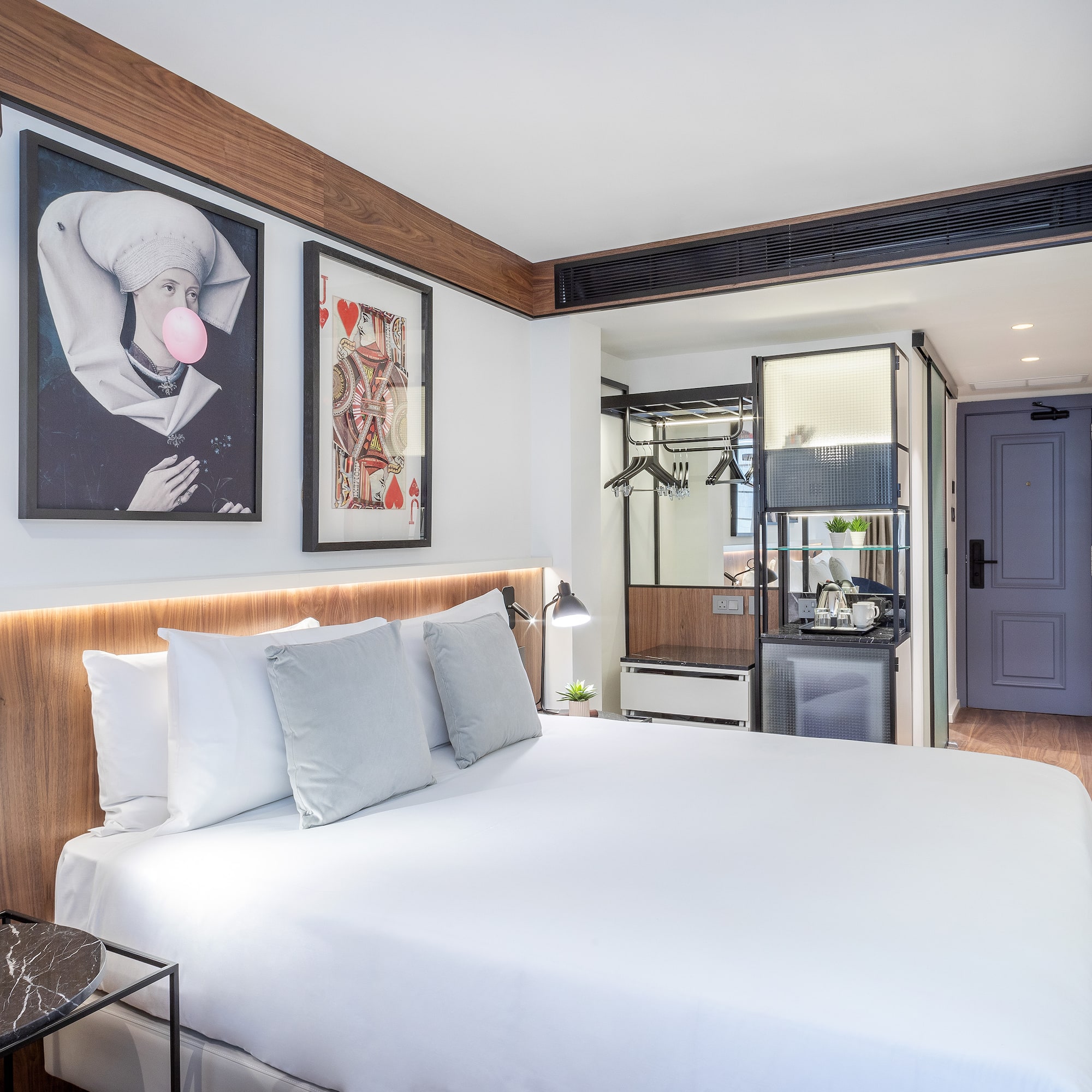 a bed with white sheets and pillows in a room with a wood floor