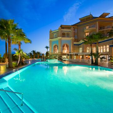 a pool with palm trees and a building