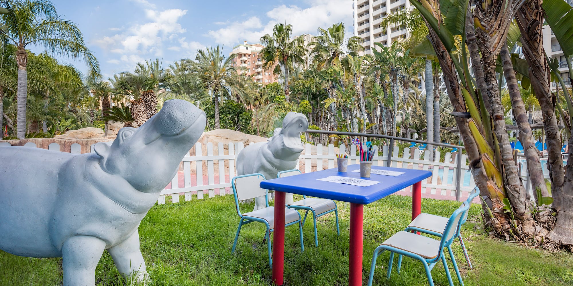 a statue of a hippo next to a table and chairs