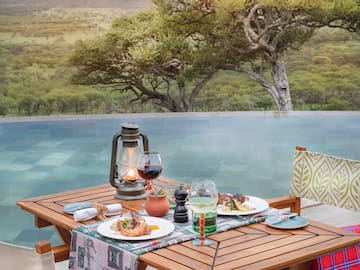 a table with food and wine glasses on it by a pool