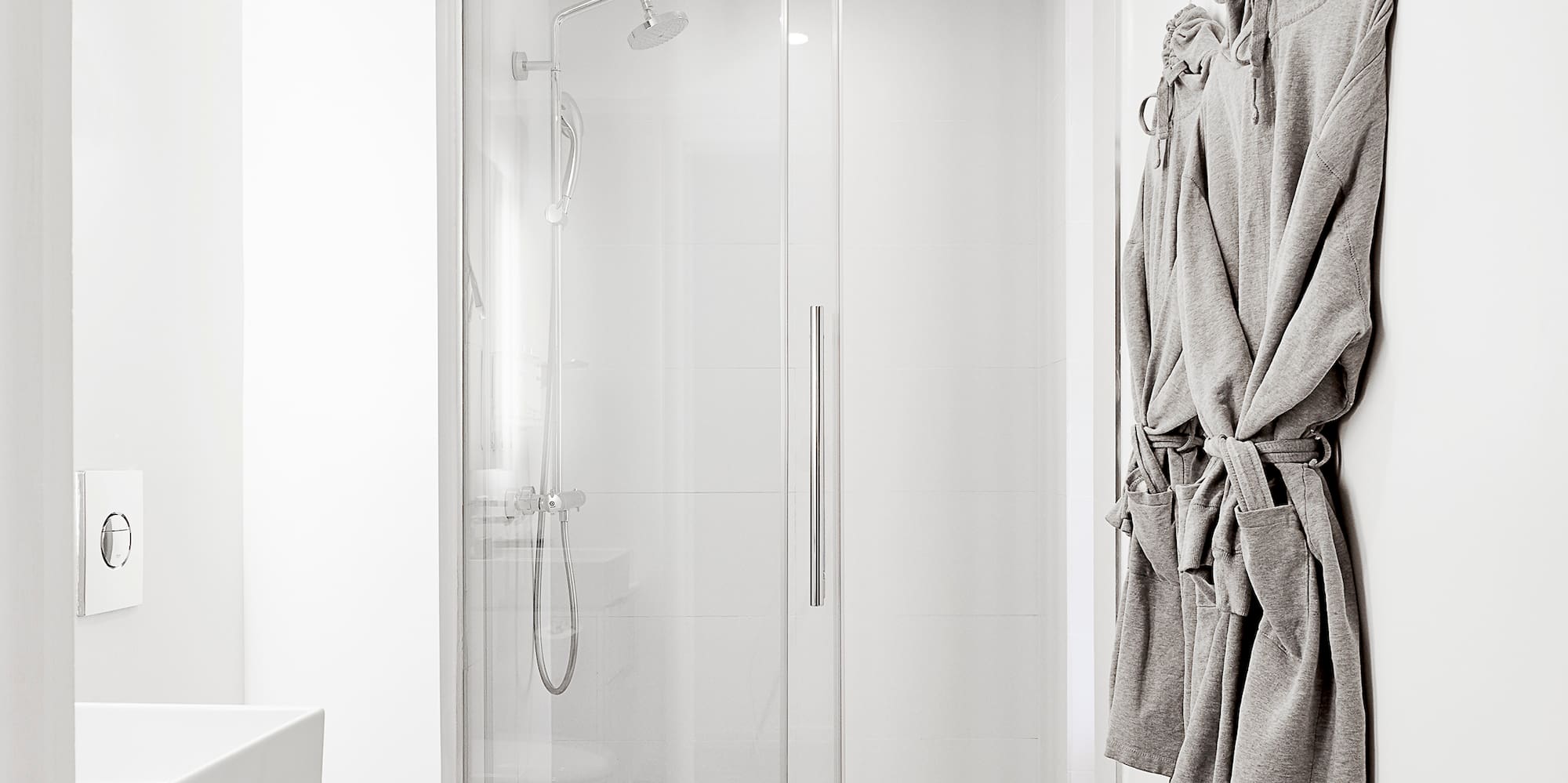 Contemporary white bathroom, glass shower, toilet, floating vanity, and grey floor.