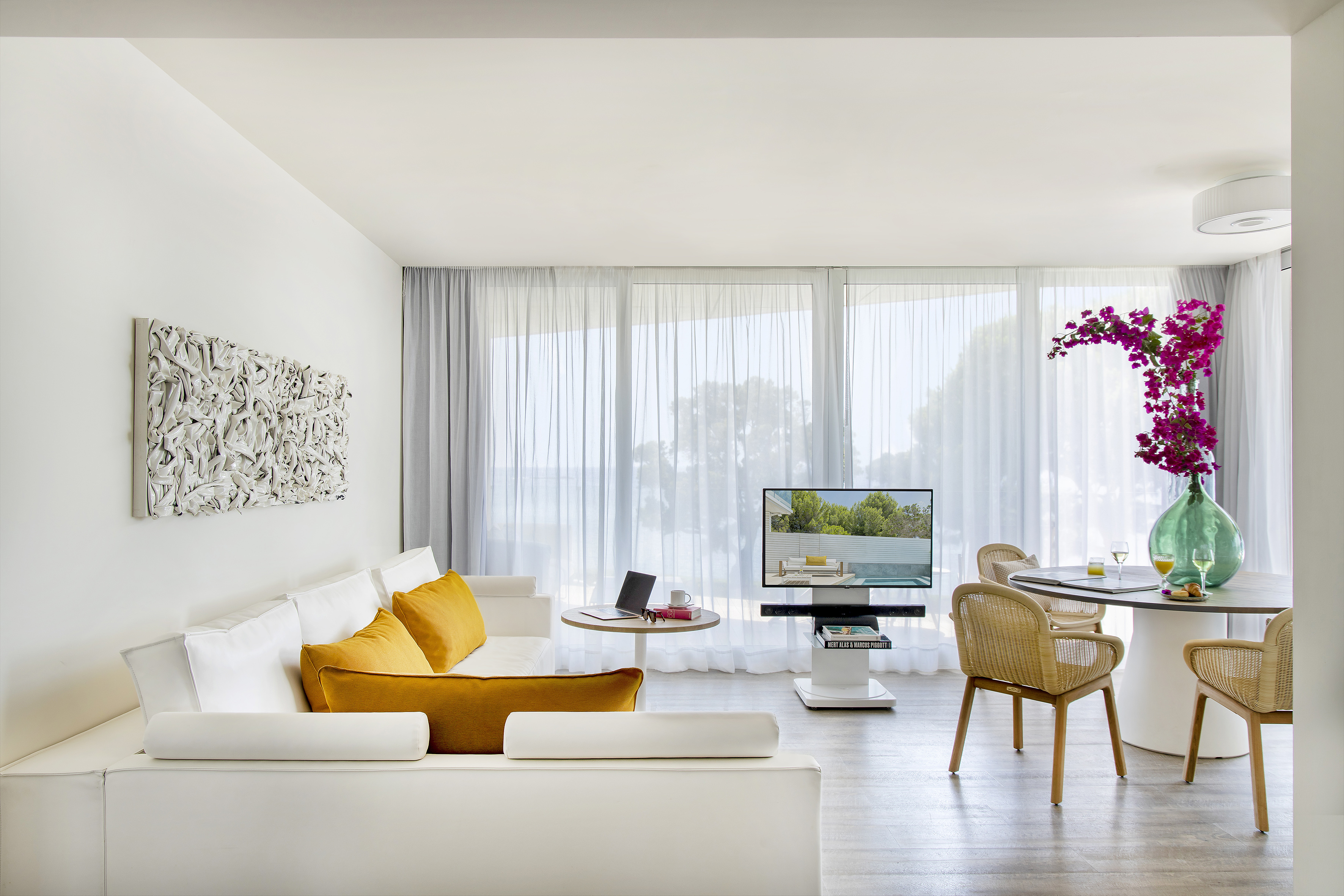 Bright modern living room suite with white sofa, dining table, and large windows.