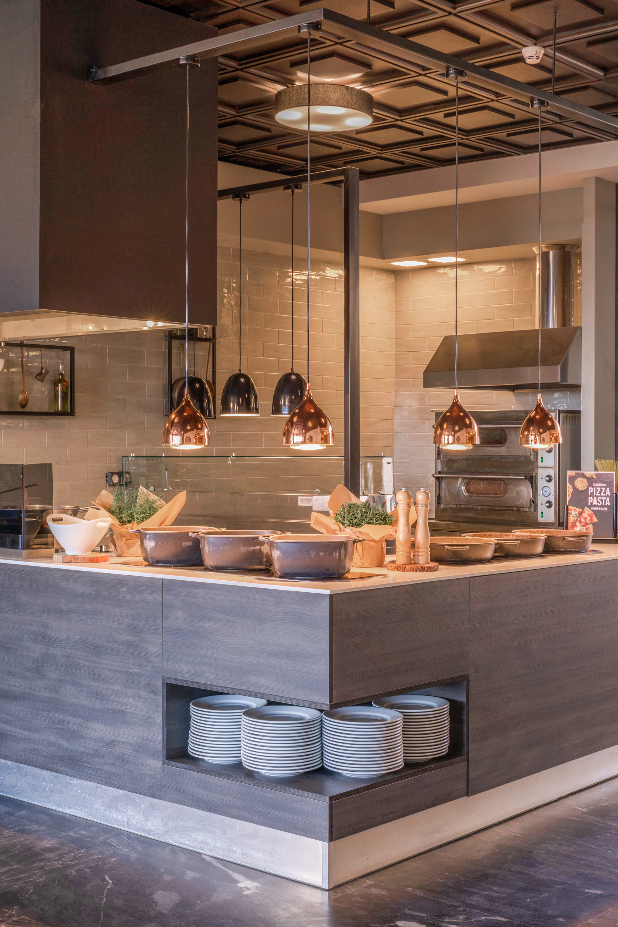 Restaurant buffet line with copper pendant lighting and pizza oven.