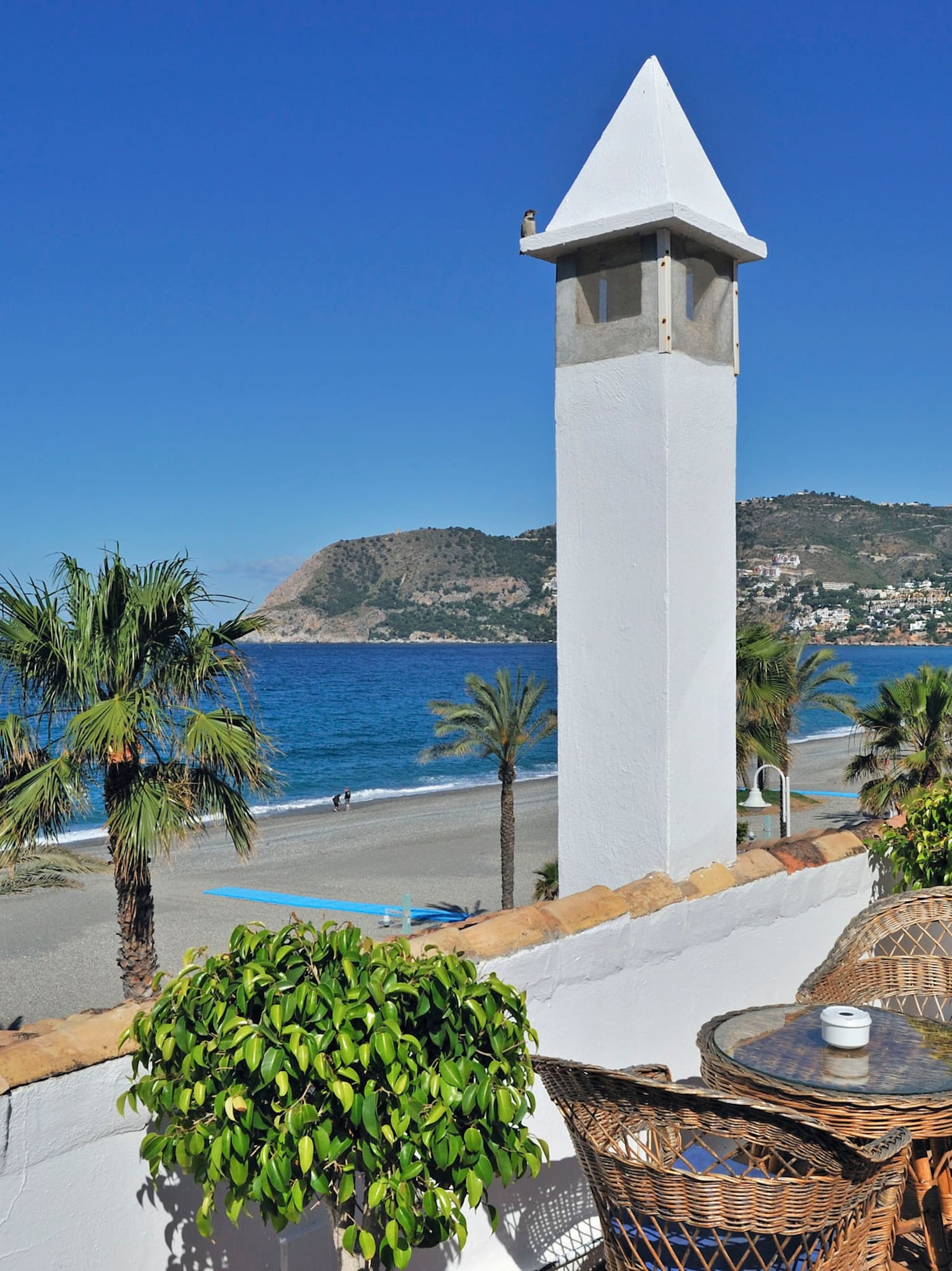 a white tower with a table and chairs on a beach