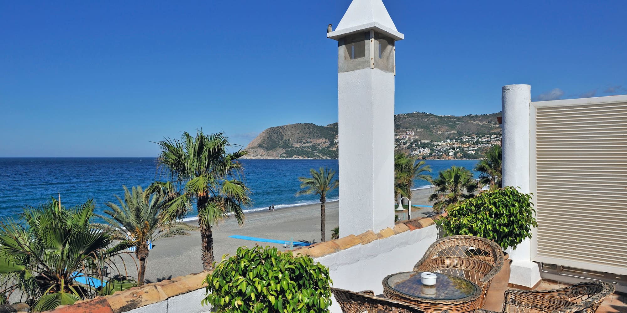 a white tower with a table and chairs on a beach