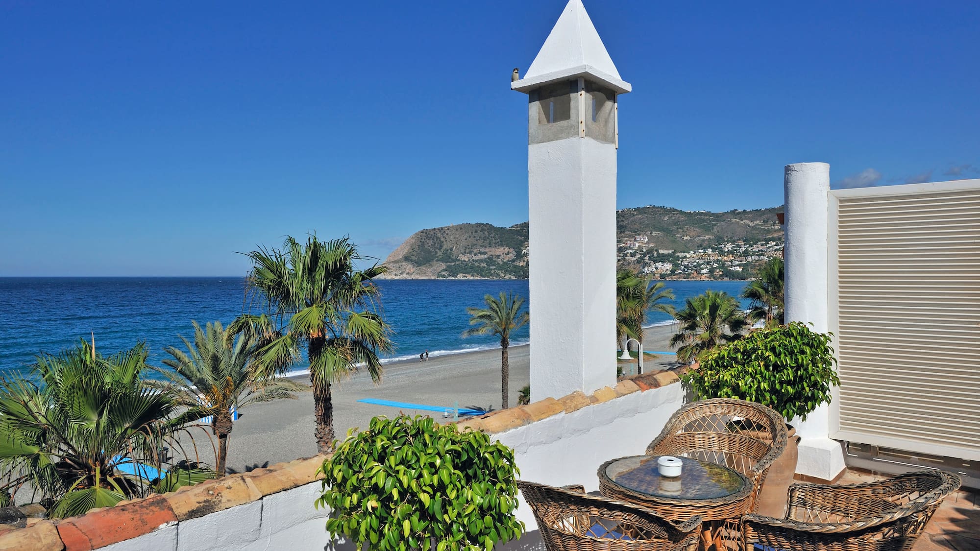 a white tower with a table and chairs on a beach