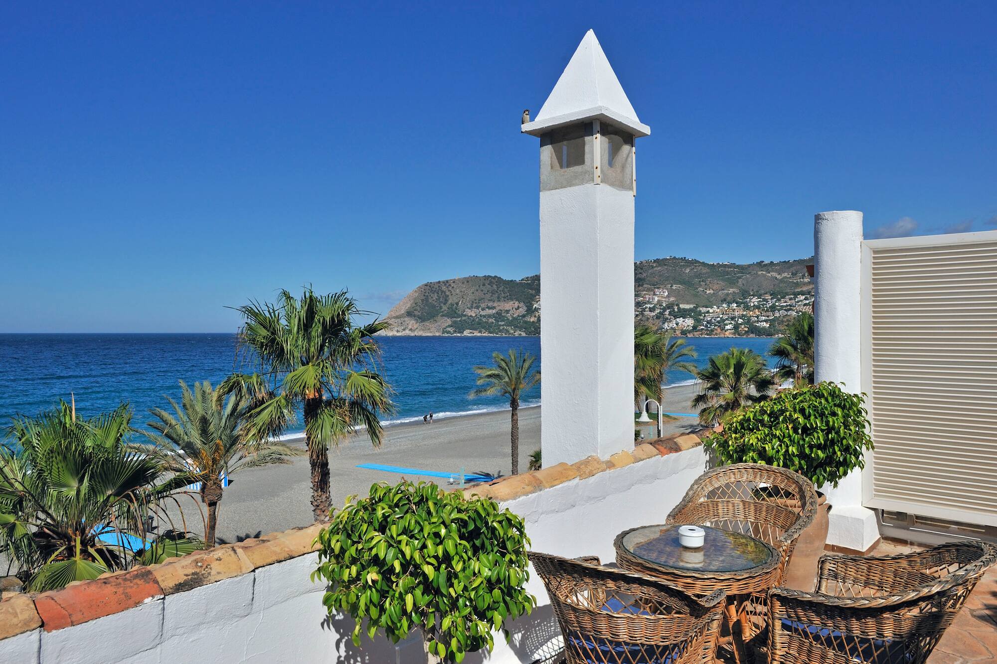 a white tower with a table and chairs on a beach