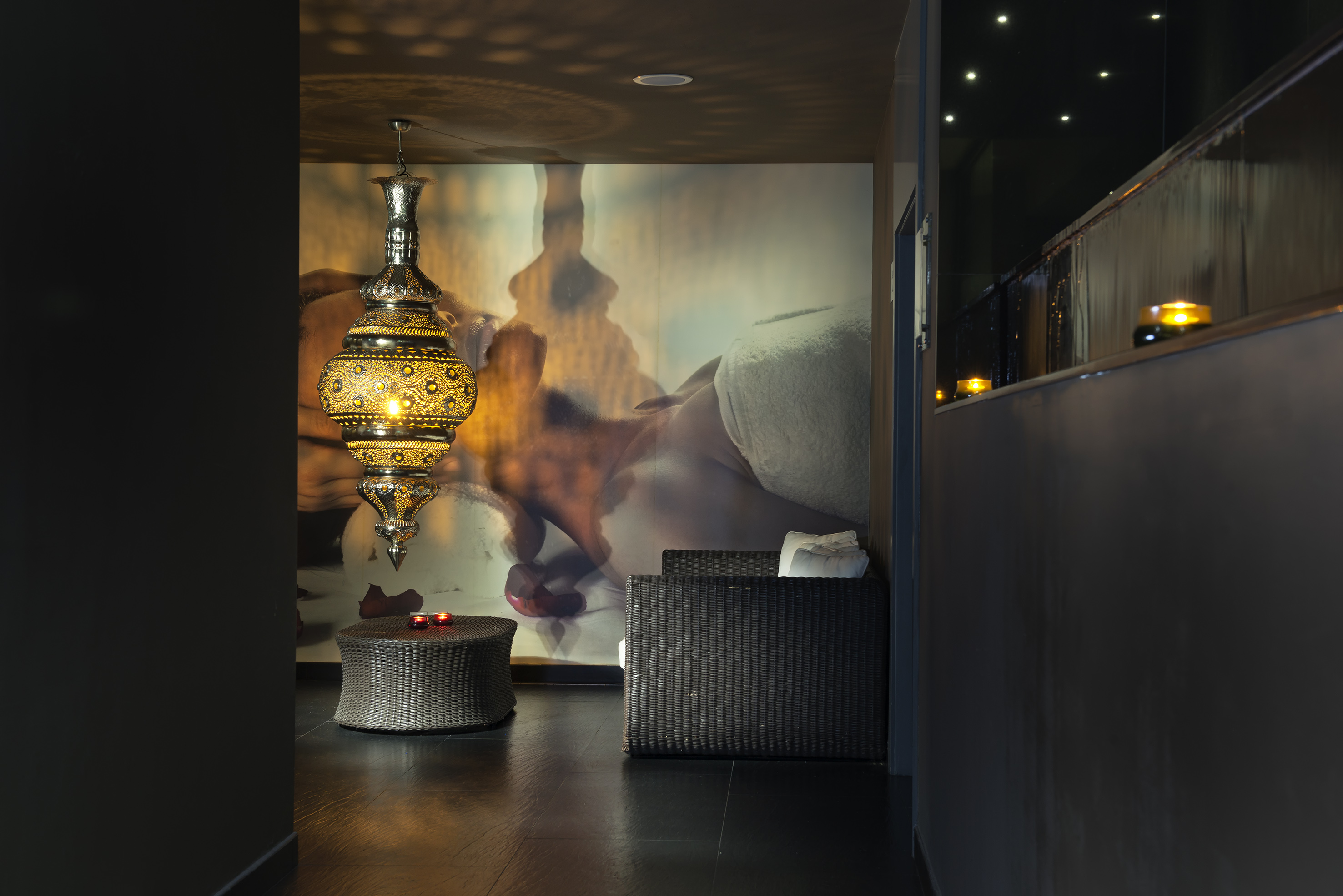 Luxury spa relaxation area with glowing Moroccan lantern and massage mural.