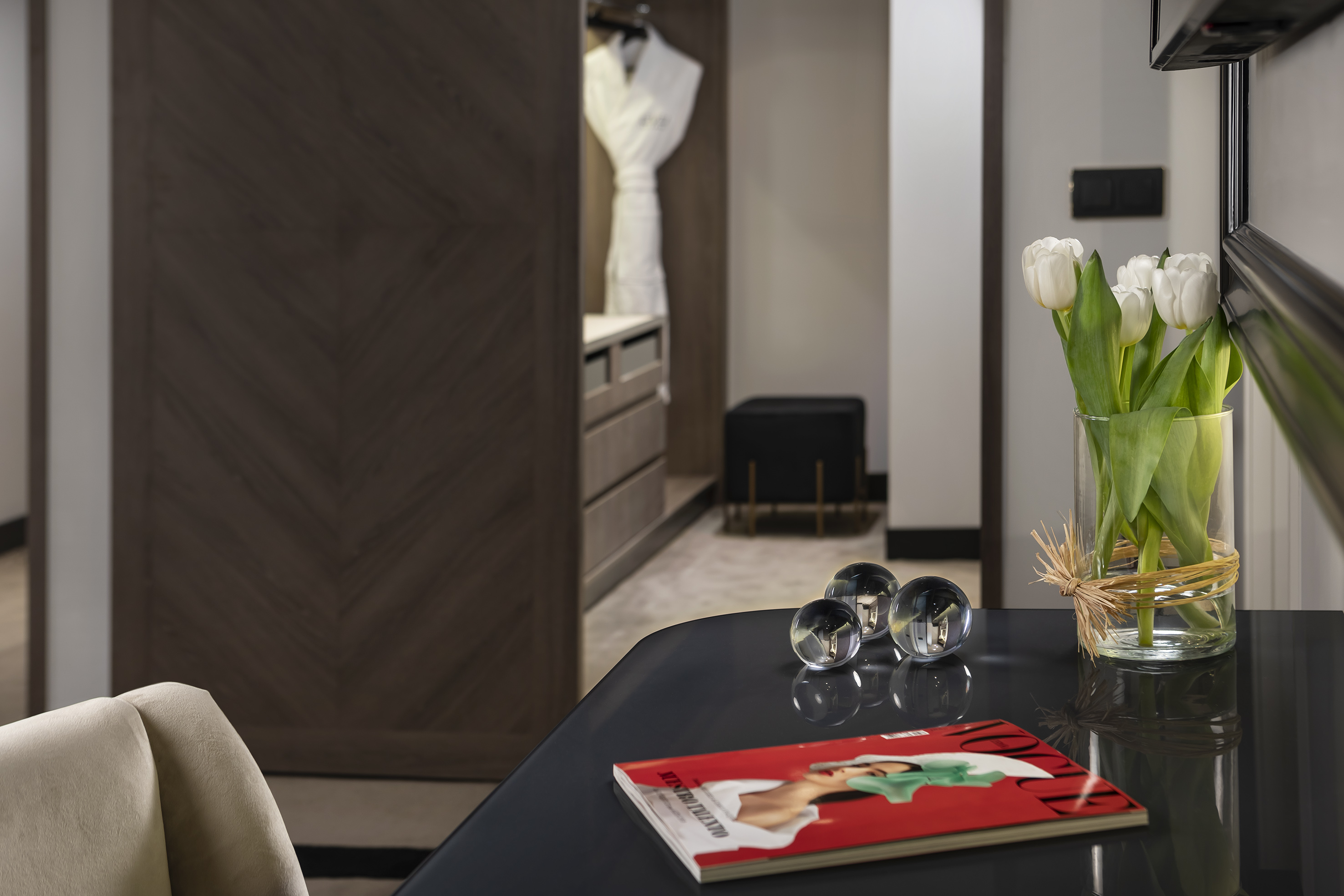 Luxury hotel room decor: white tulips, magazine, and open closet.