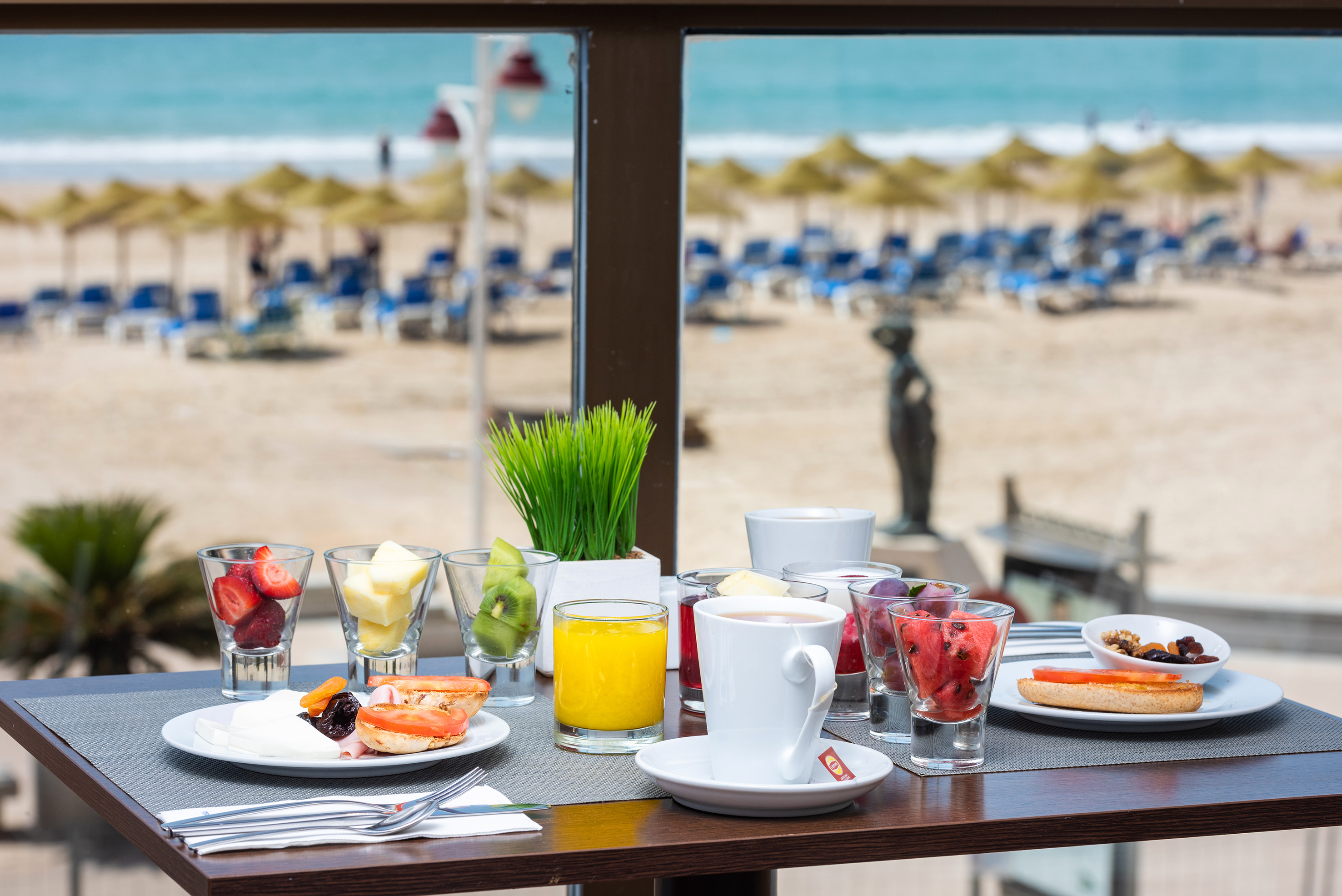Beachfront breakfast with fresh fruit, juice, and coffee, overlooking the ocean.