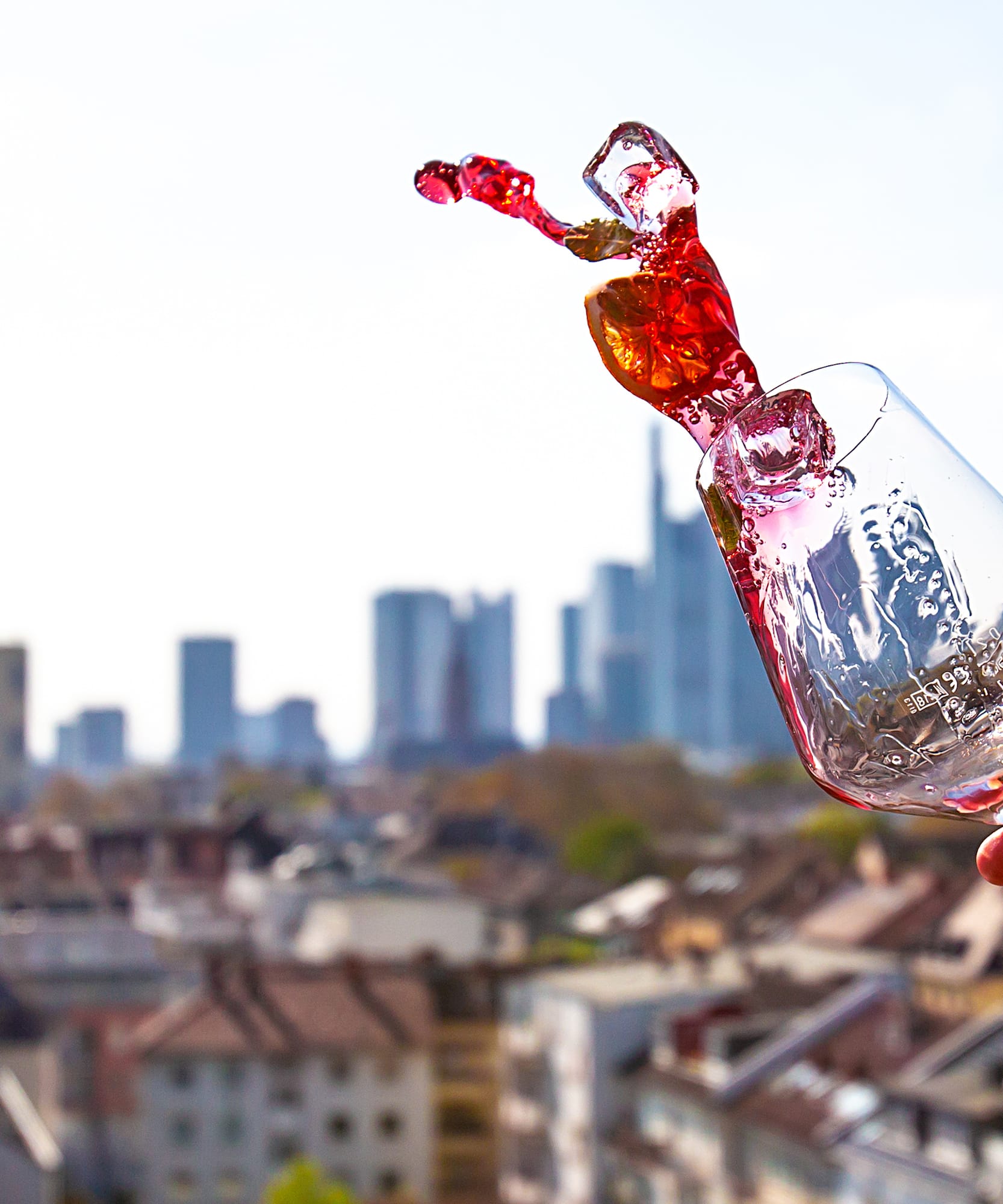a hand holding a glass with a red liquid in it