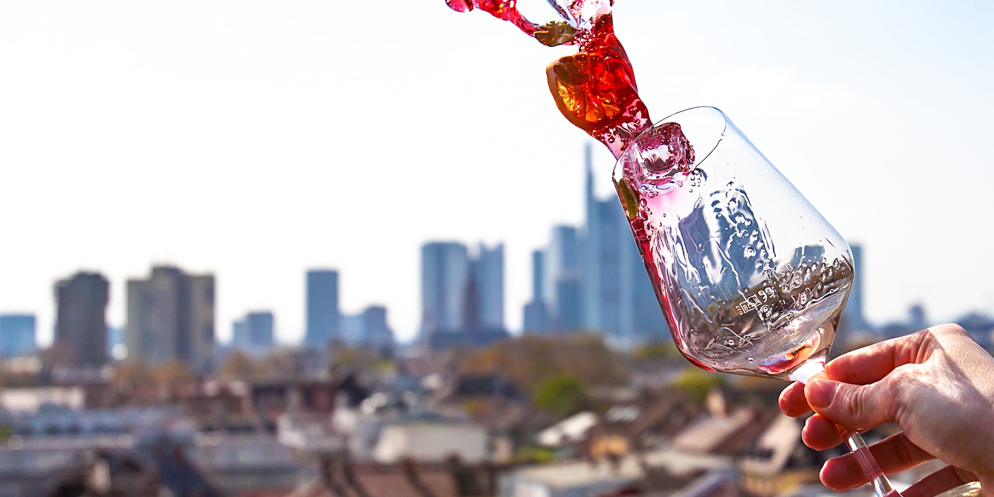 a hand holding a glass with a red liquid in it