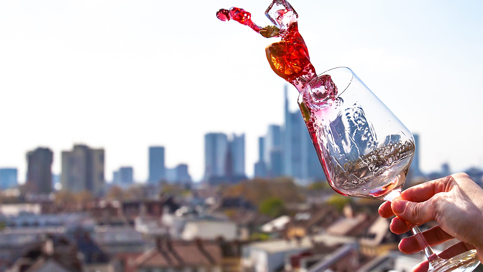 a hand holding a glass with a red liquid in it