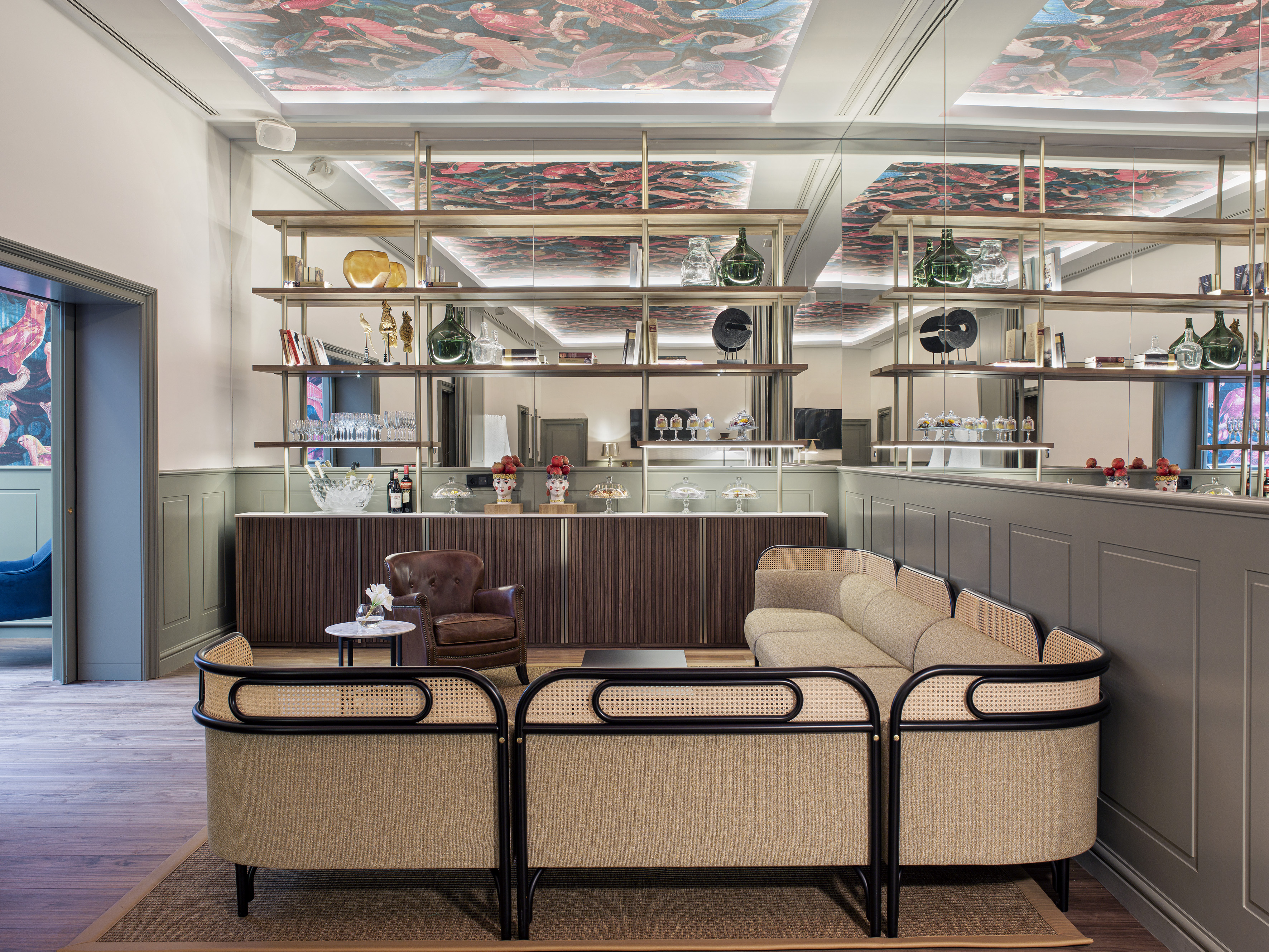 Sophisticated lounge bar with ornate ceiling, cane sofa, and mirrored shelving.