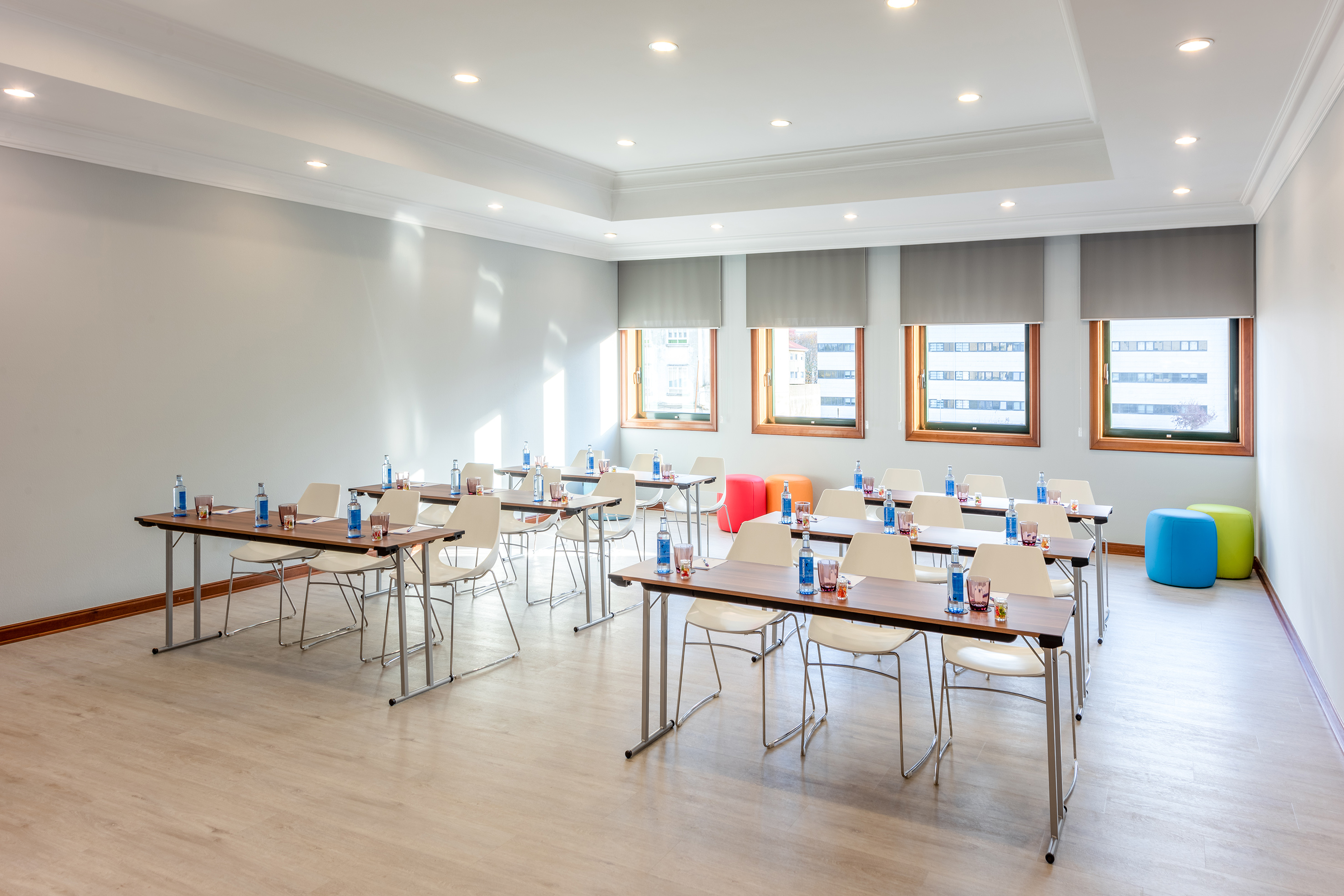 Modern training classroom with tables, chairs, water bottles, and windows.
