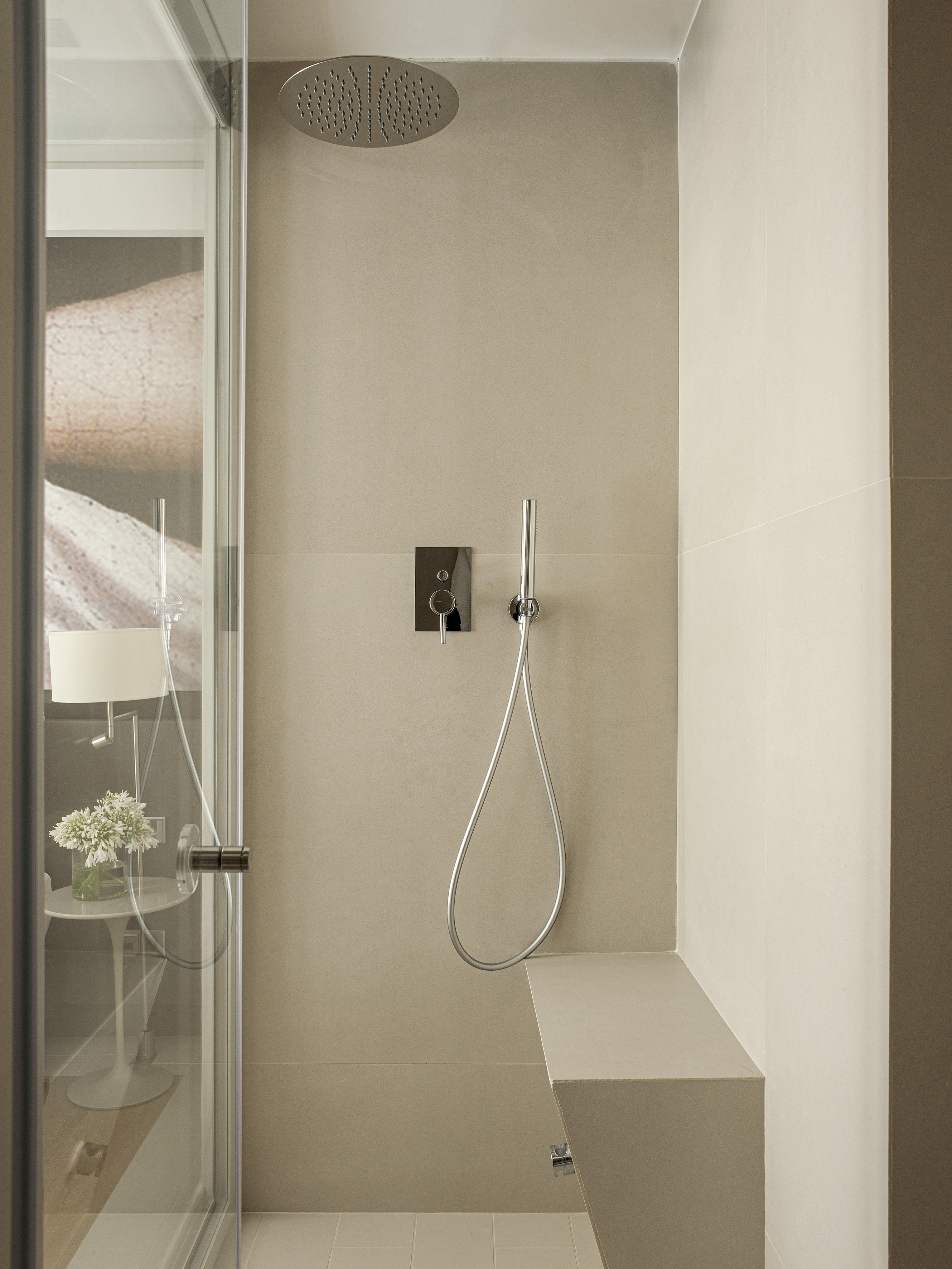 Modern beige tiled walk-in shower with rain showerhead and built-in bench.