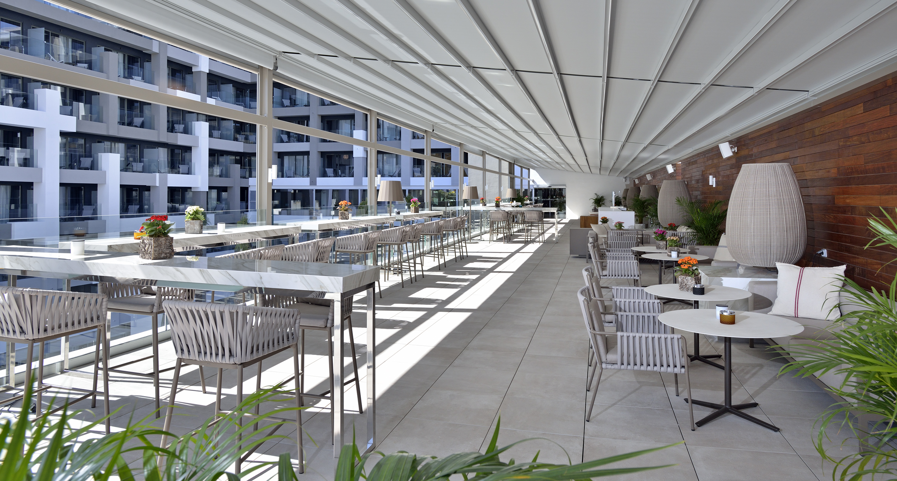 Modern rooftop bar and lounge with retractable roof, sleek outdoor seating.