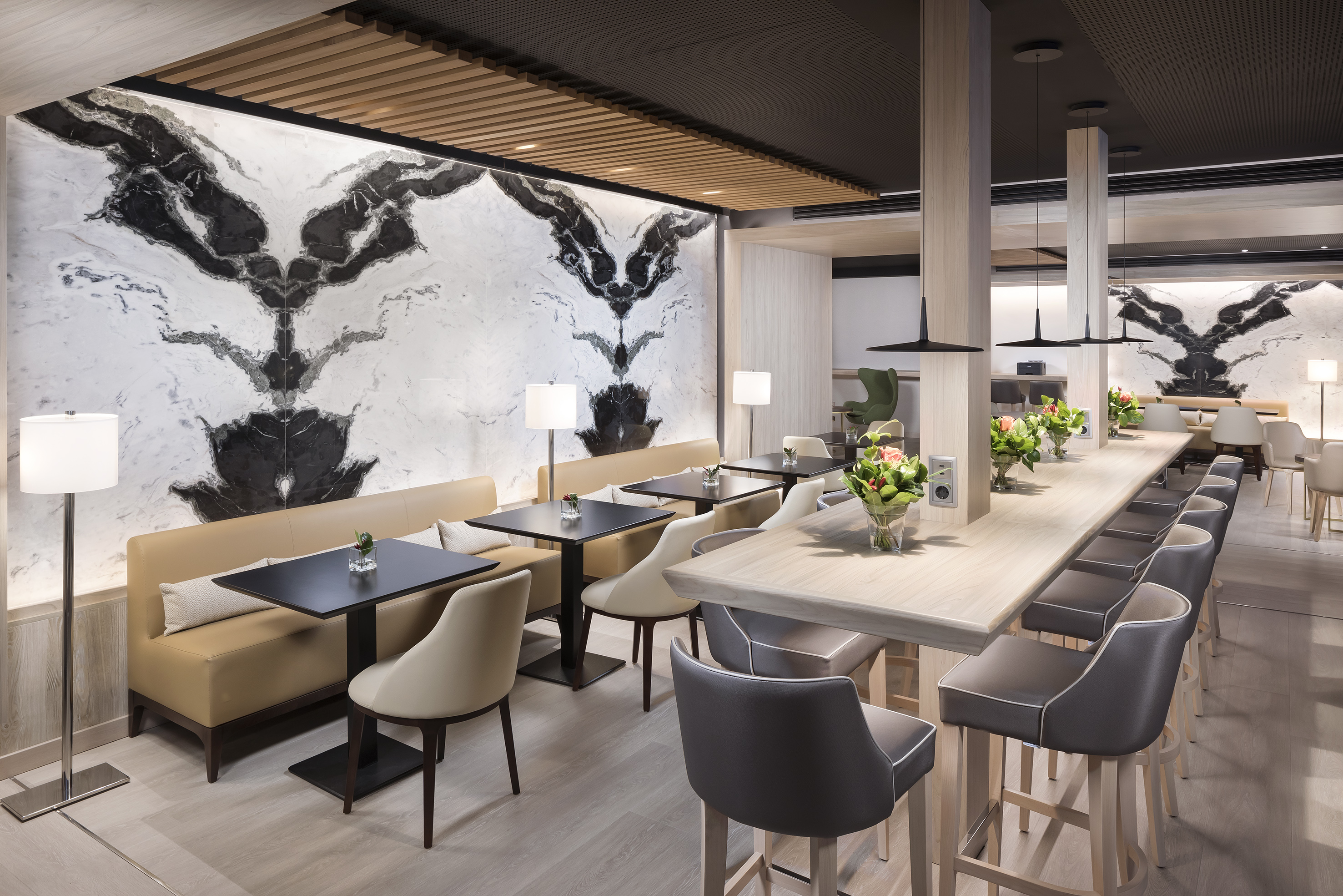 Modern lounge interior with marble feature wall, banquette seating, and long bar.