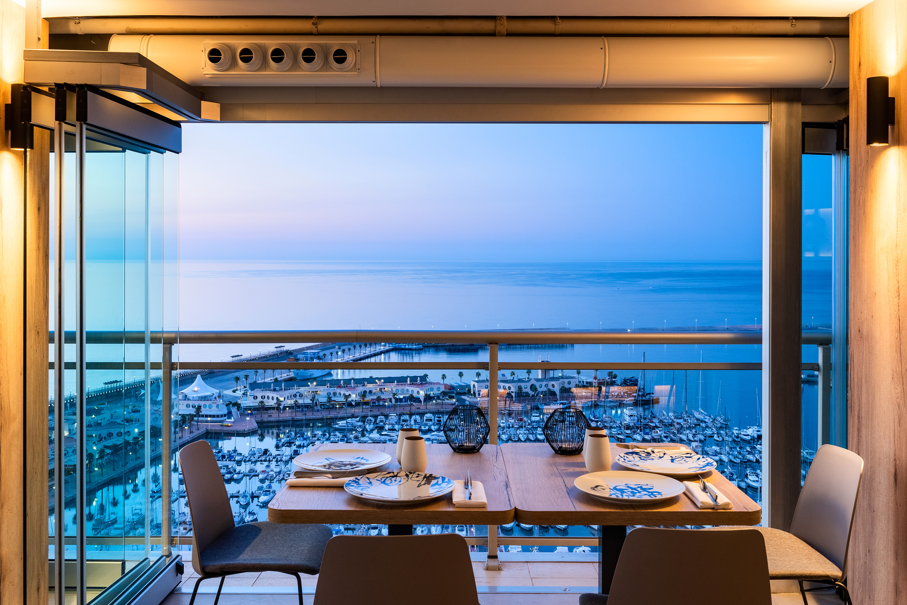 Balcony dining table with marina and sea view at twilight.