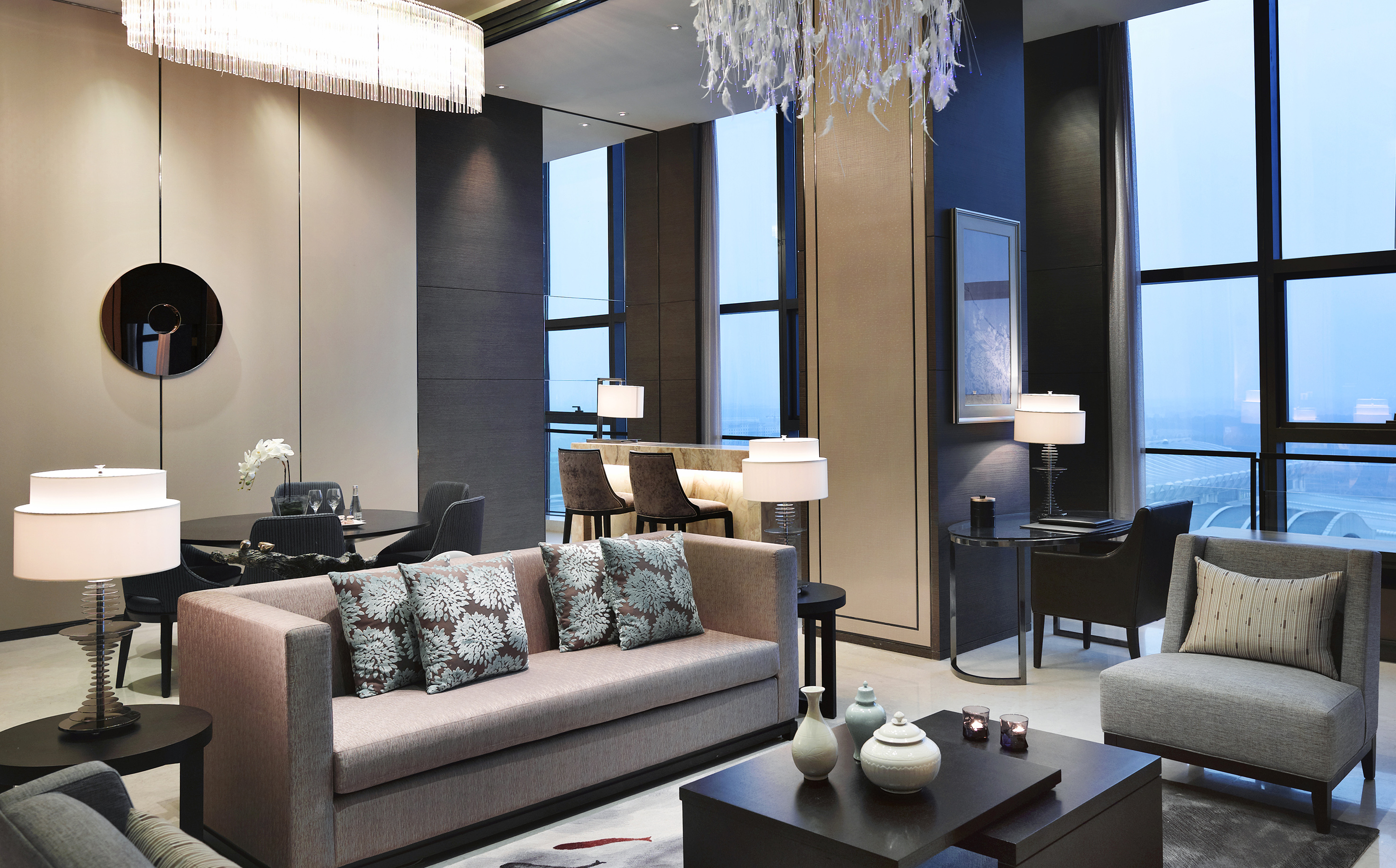 Upscale living room with modern sofa, bar, dining, and city views.