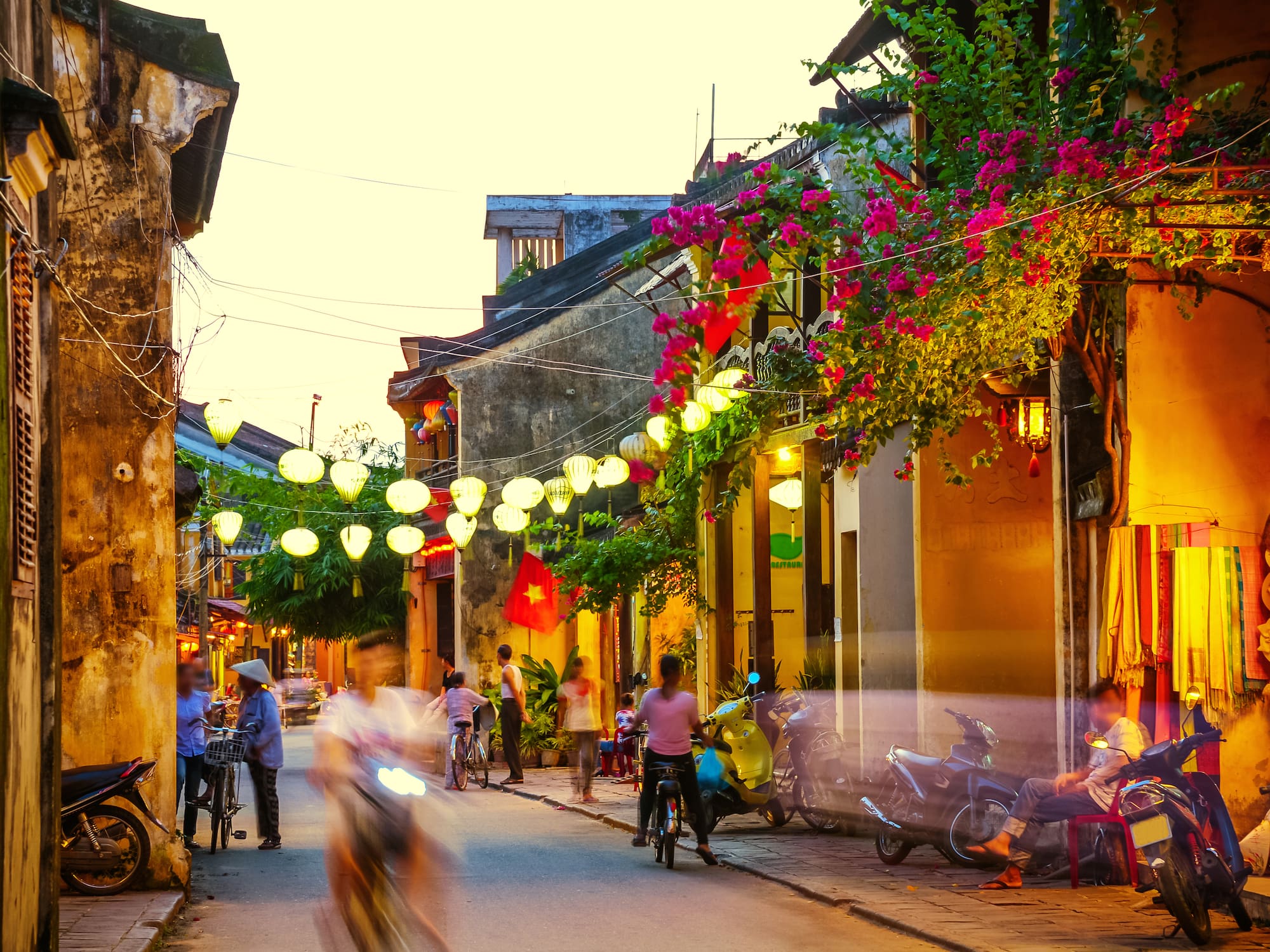 a street with people and motorcycles and lights