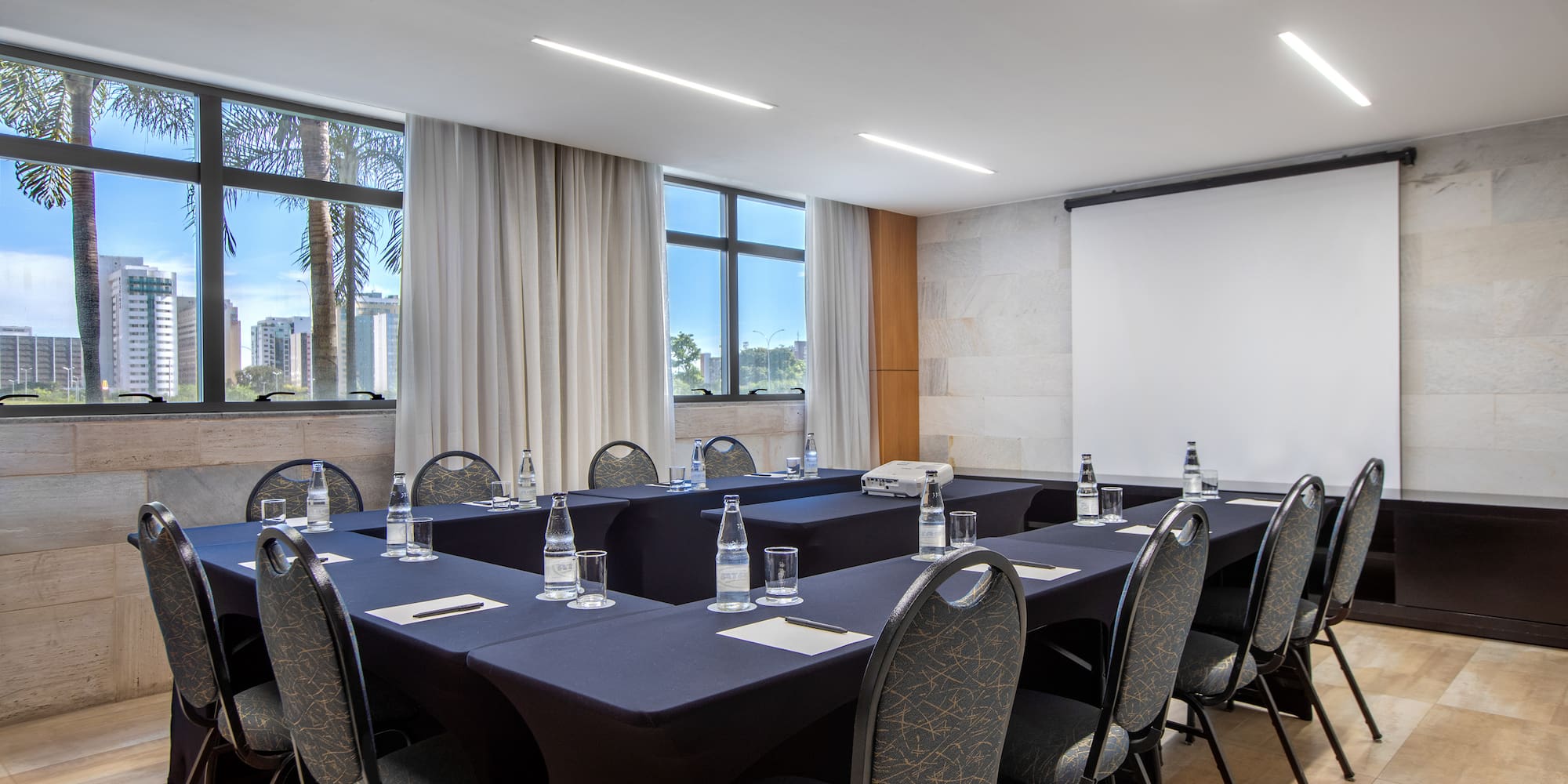 a room with a projection screen and tables and chairs