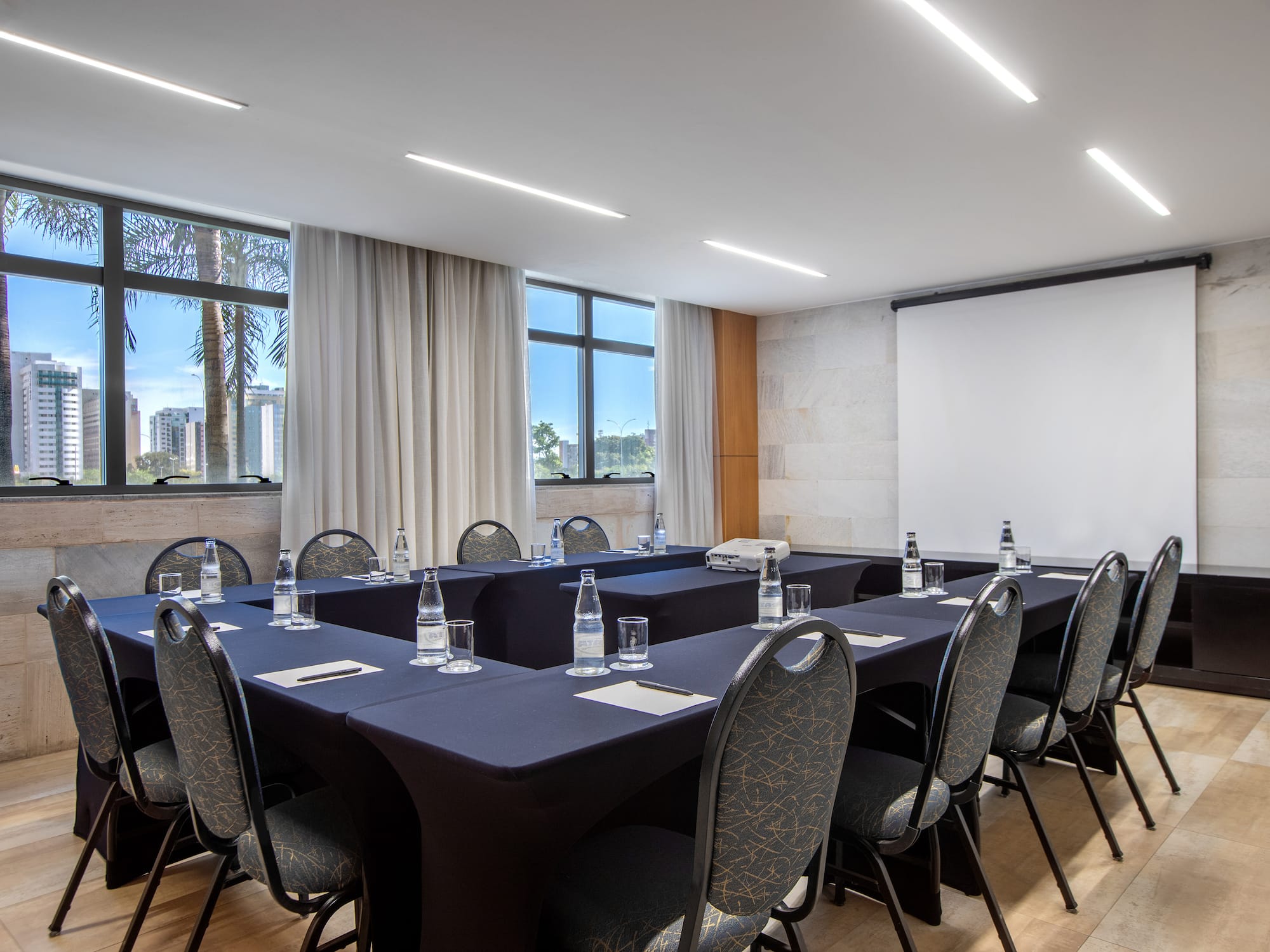 a room with a projection screen and tables and chairs.