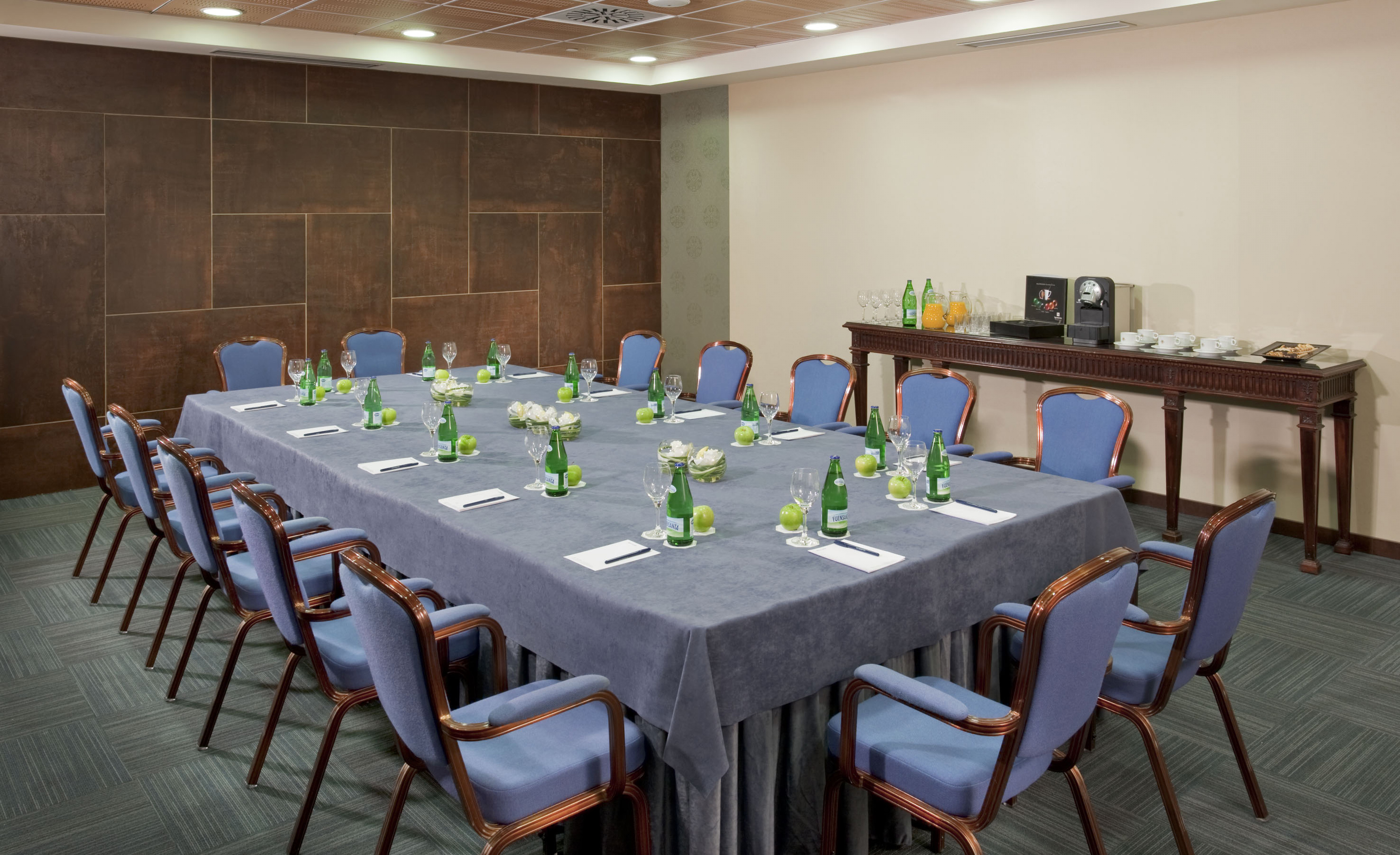Conference room with blue chairs, table setup, and refreshments.