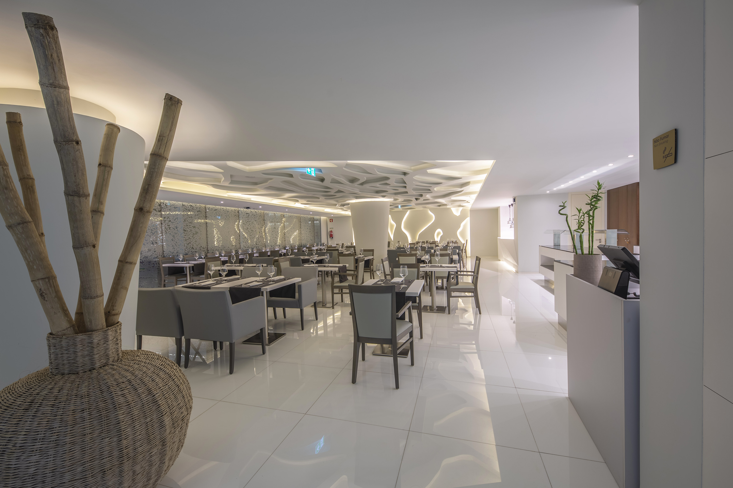 Modern restaurant dining area with white floor, patterned ceiling, and bamboo decor. - Lores, Internationale keuken - Meliá Maputo Sky, Maputo