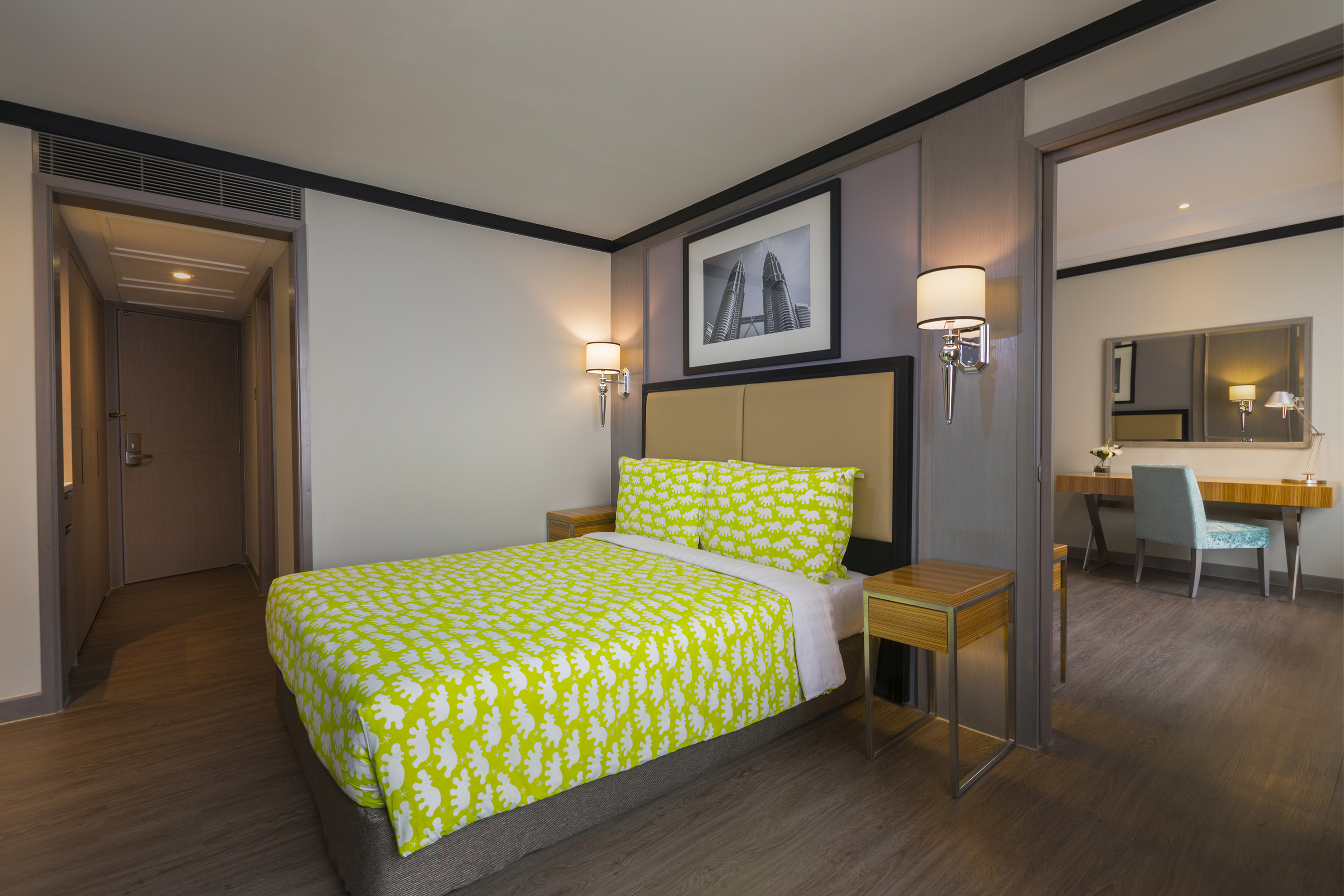 Hotel room with lime green bed, Petronas Towers art, and desk area.