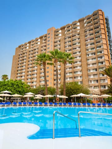 a large building with a pool and palm trees