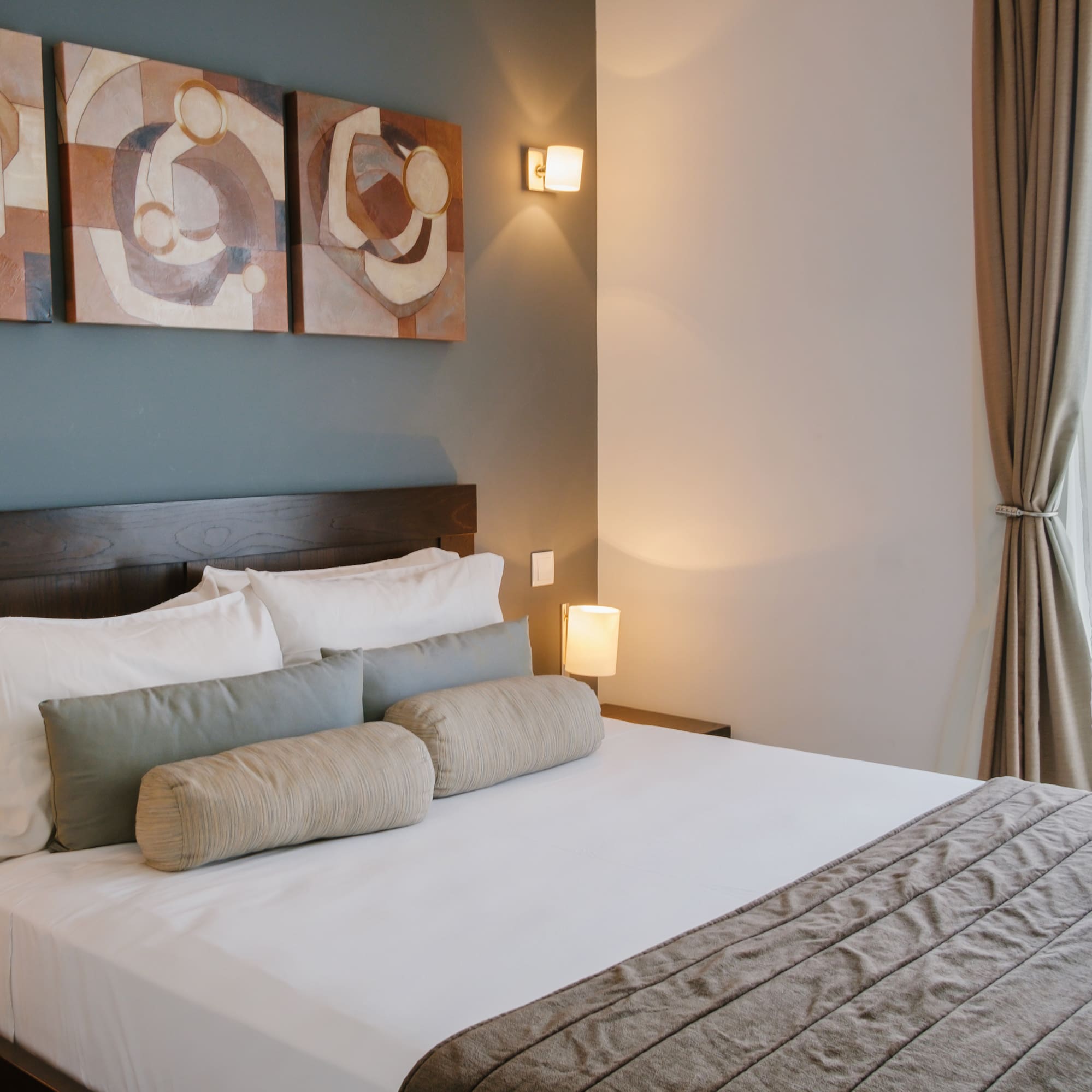 a bed with pillows and a lamp on the wall