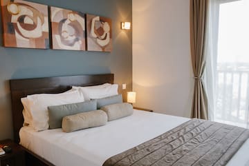 a bed with pillows and a lamp on the wall