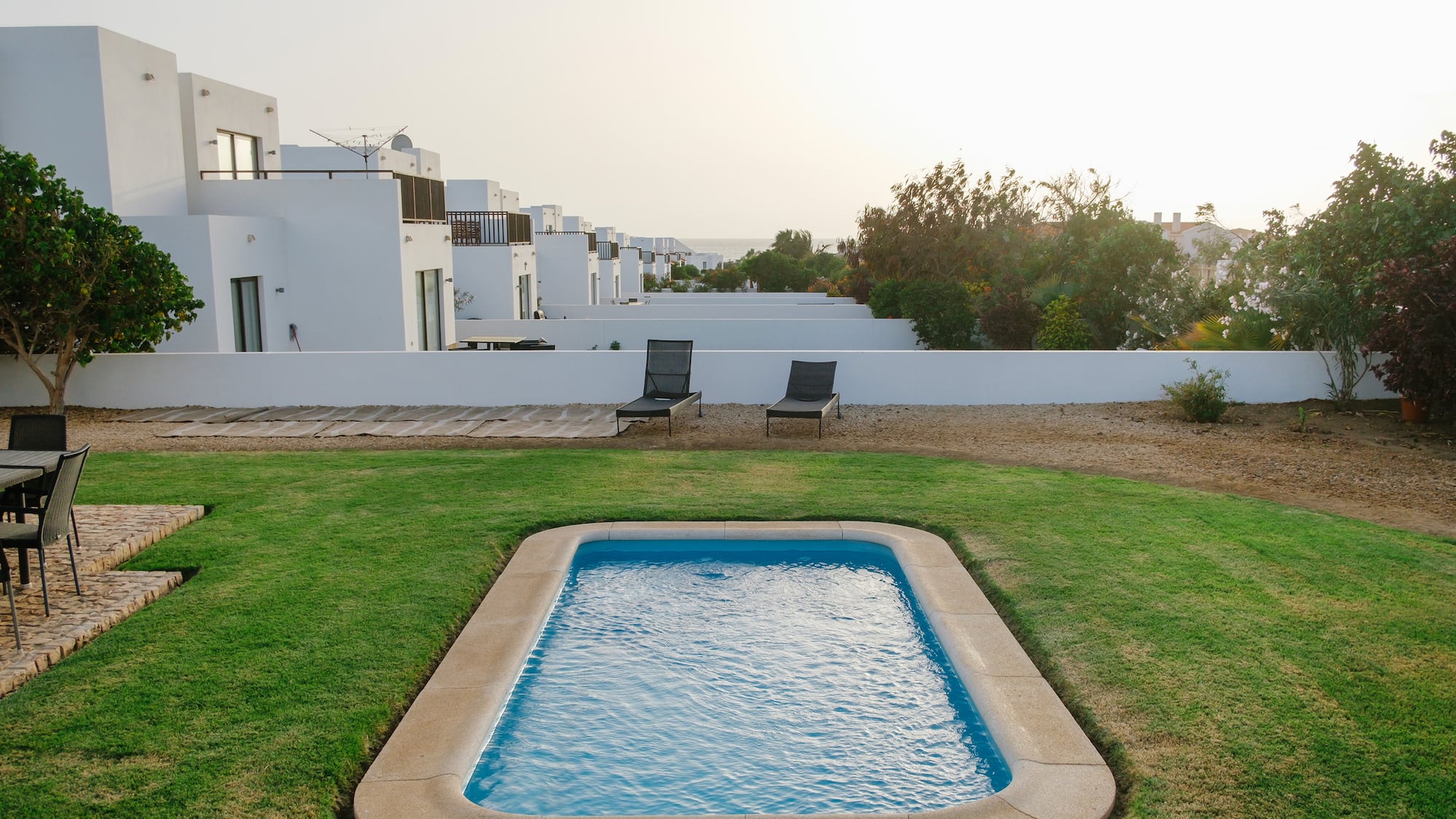 a pool in a yard with white buildings in the background