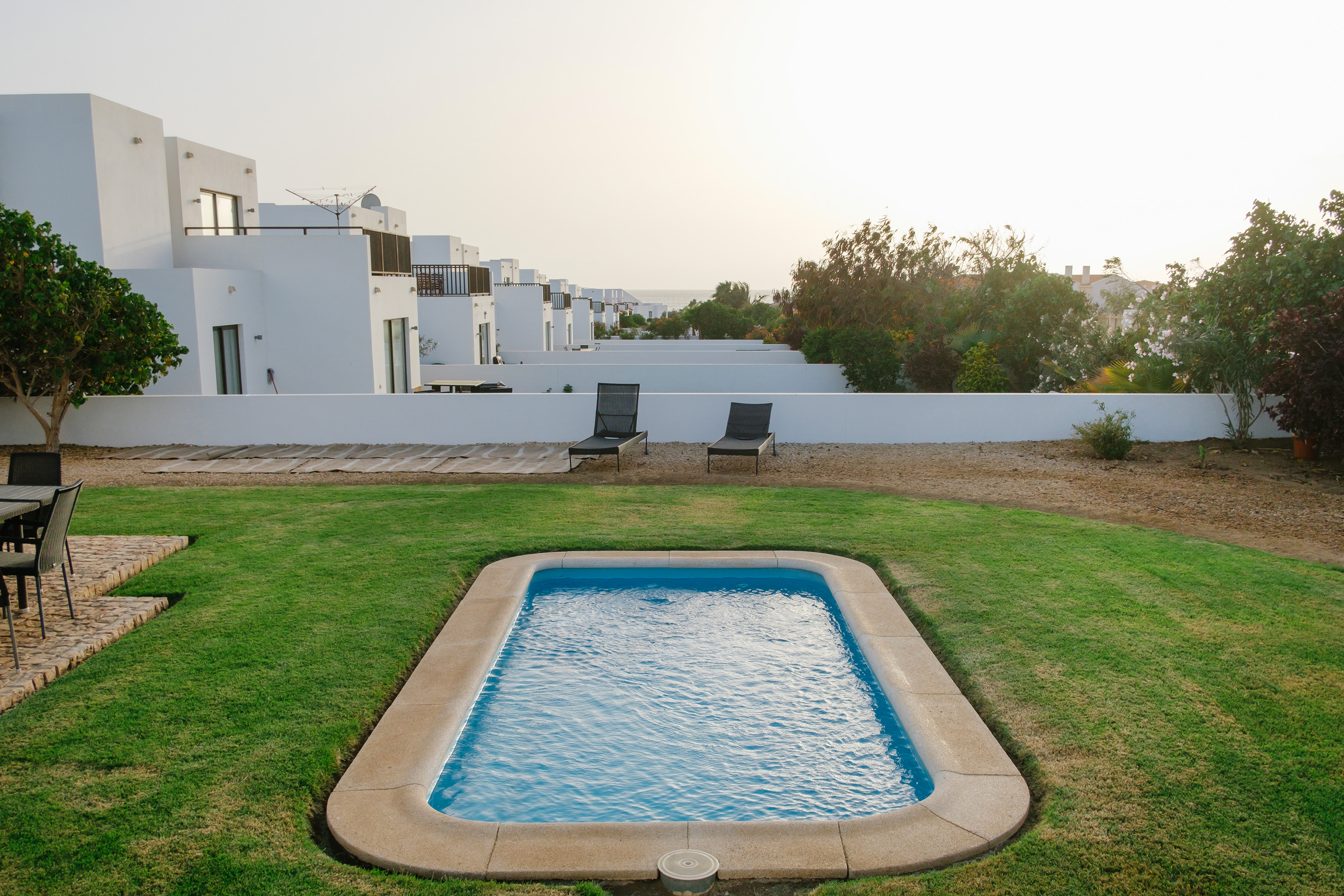 a pool in a yard with white buildings in the background